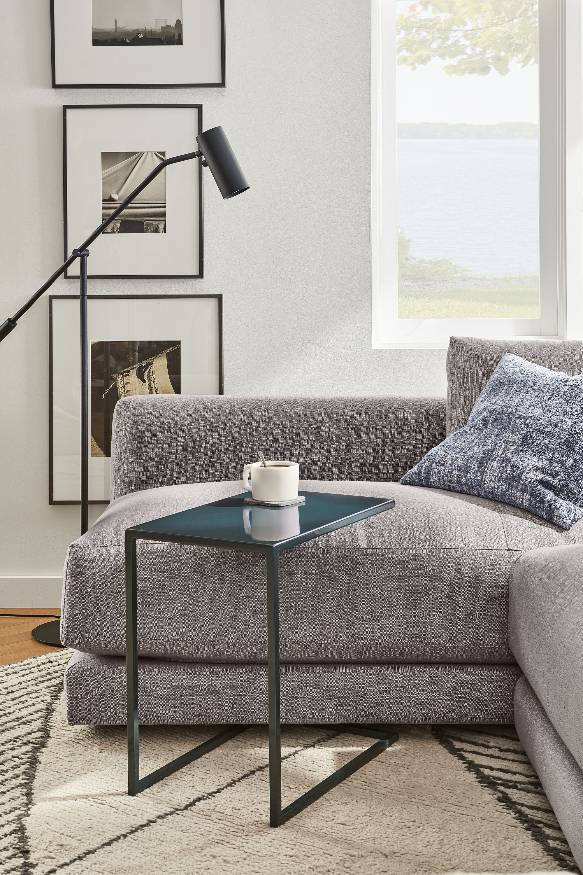 Living room image with slim c-shaped table in slate with safi rug in grey.