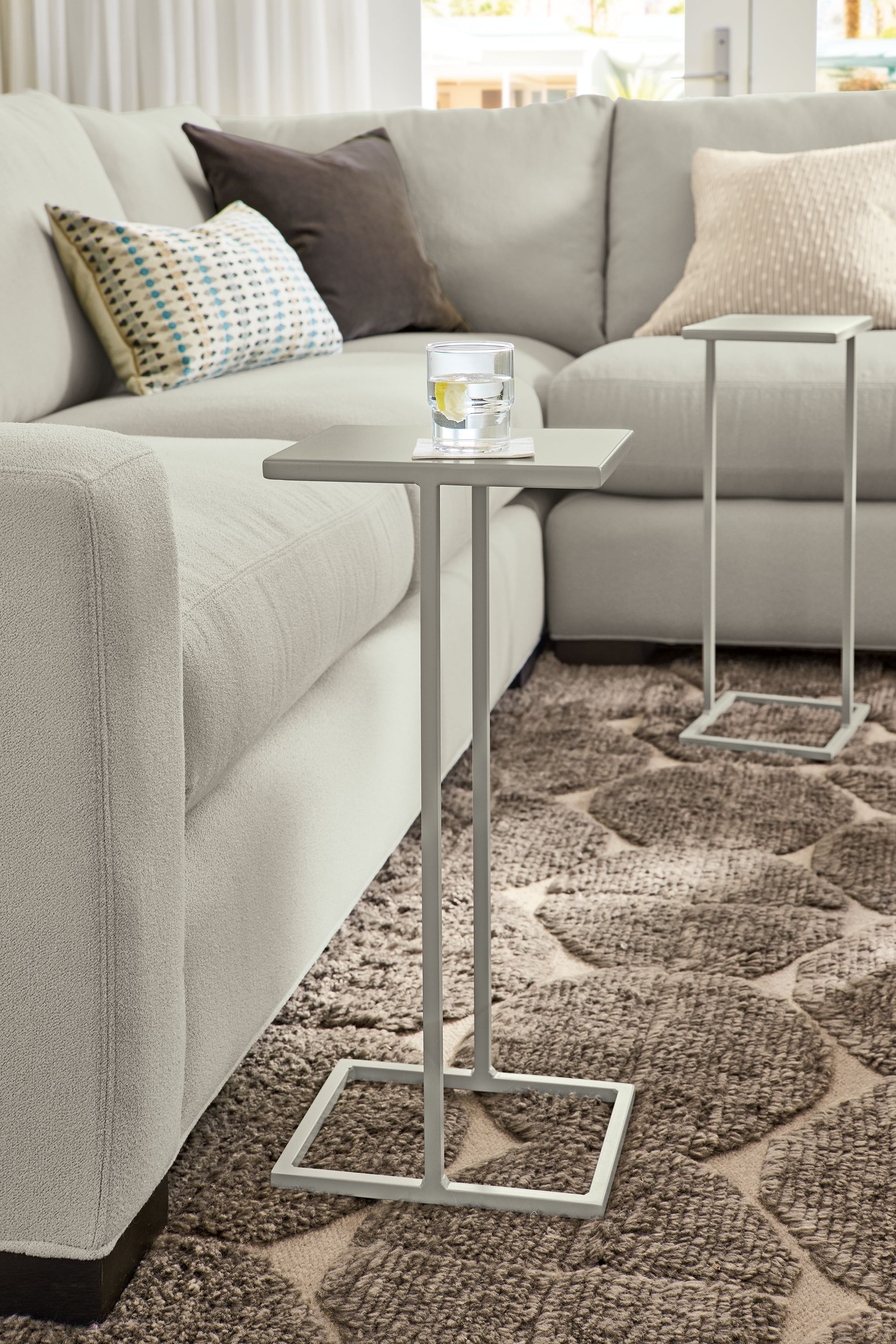 Living room with detail of 2 Slim 10-wide C-tables in taupe, Edo rug in Putty and Metro sofa in Dusk Fog.