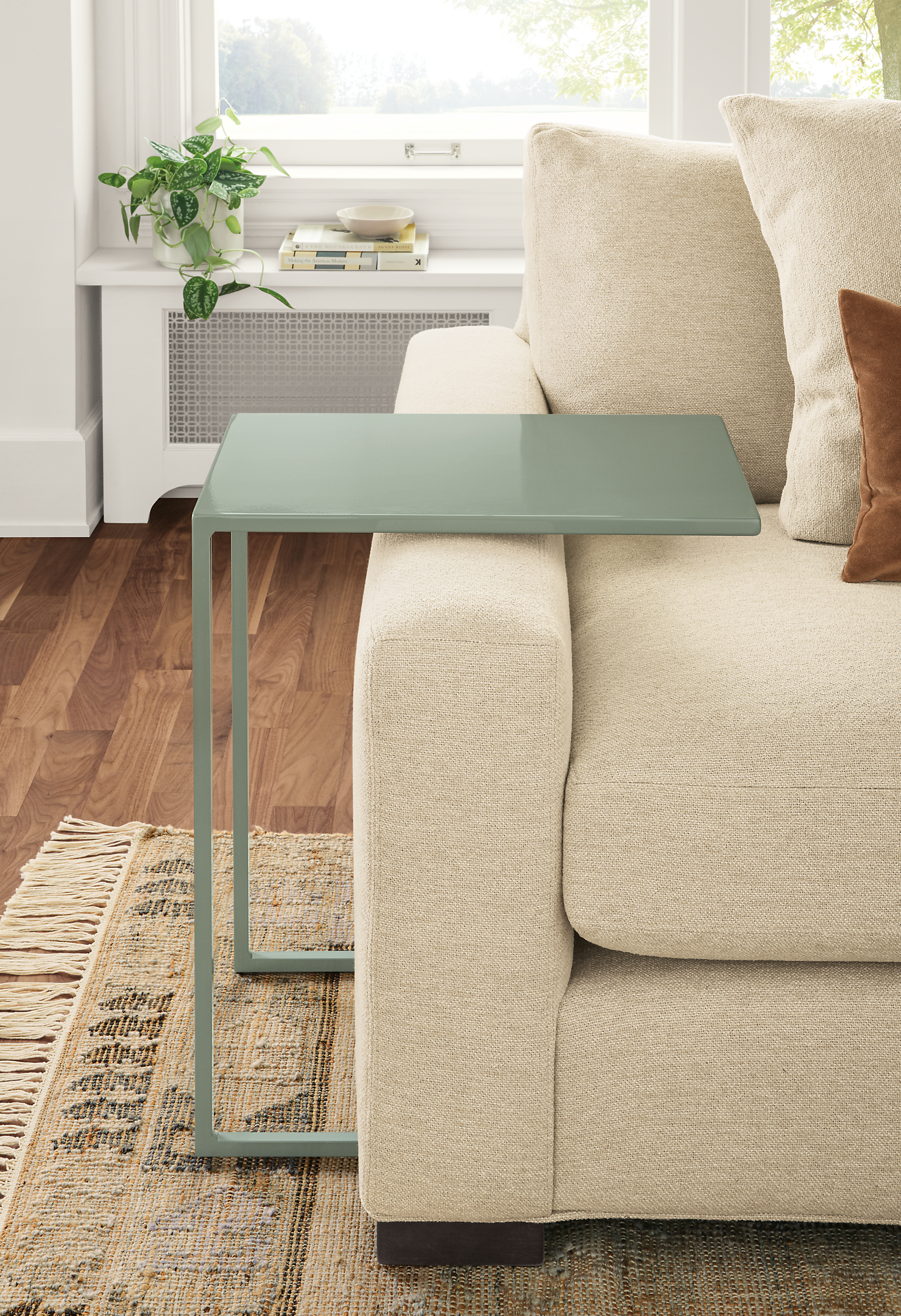 Detail of Slim C-table in Sage beside taupe sofa.