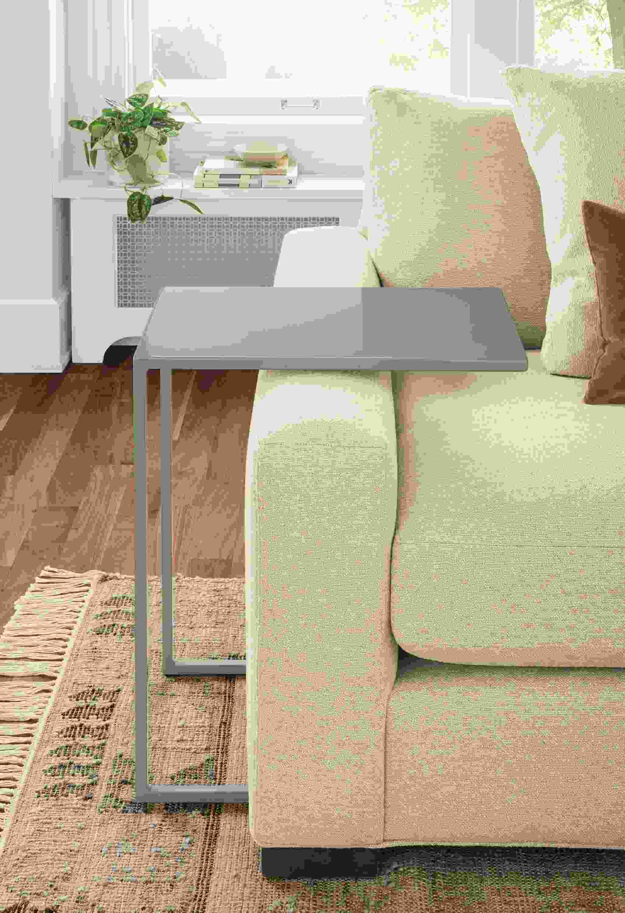 Detail of Slim C-table in Sage beside taupe sofa.