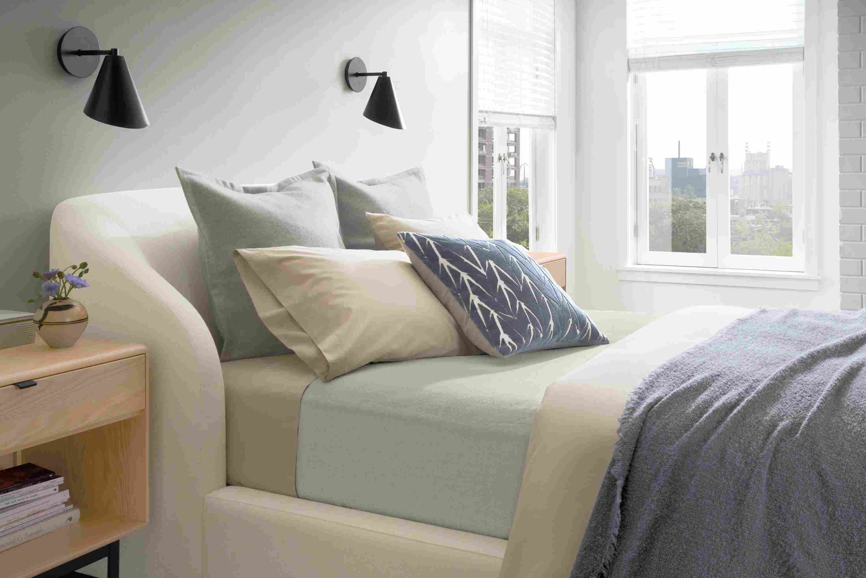 Bright apartment bedroom with soft-washed percale duvet set in stone and Mercer washable wool blanket on a bed.