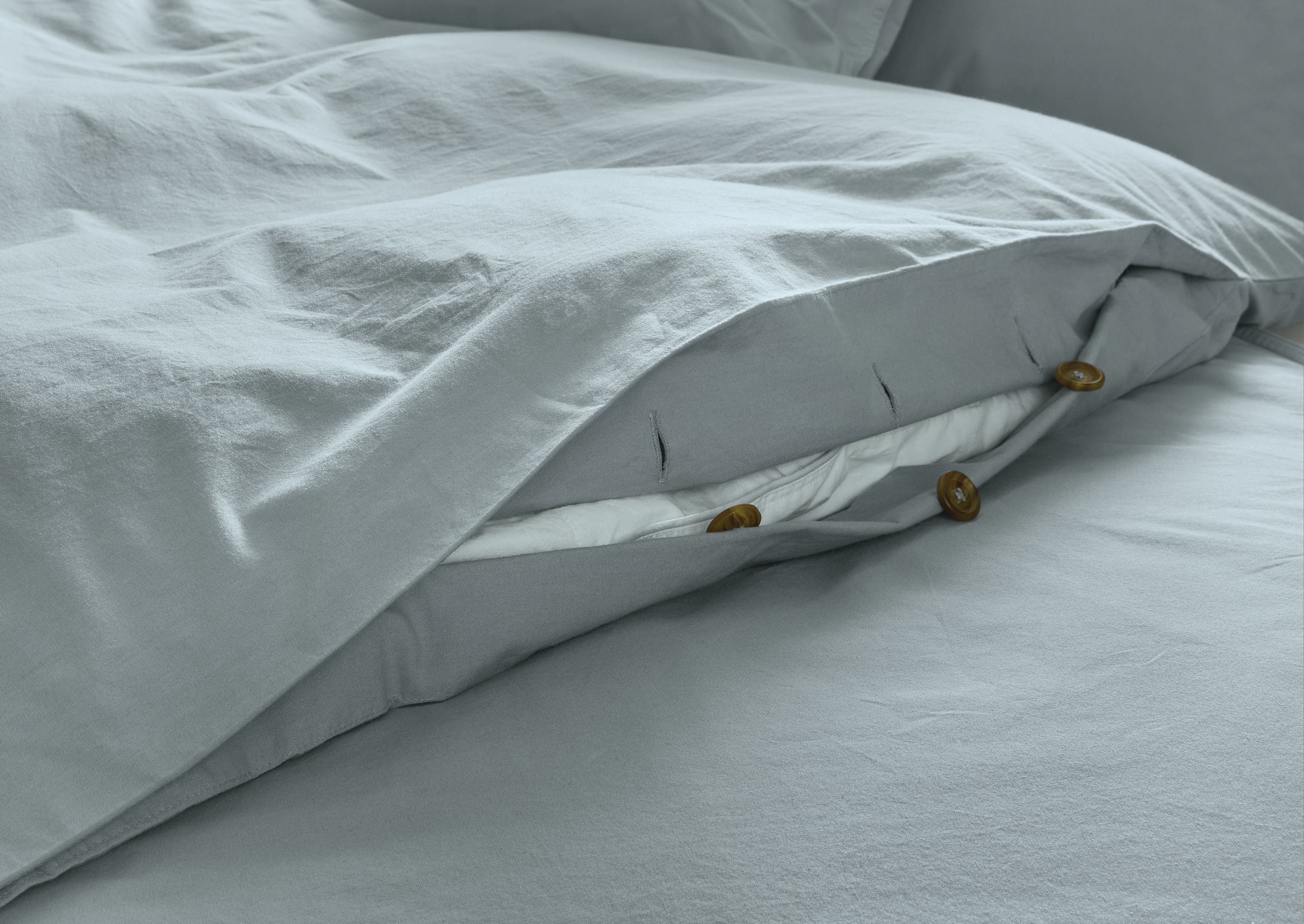Detail of button closure on soft-washed percale full/queen duvet set in lake colorway.