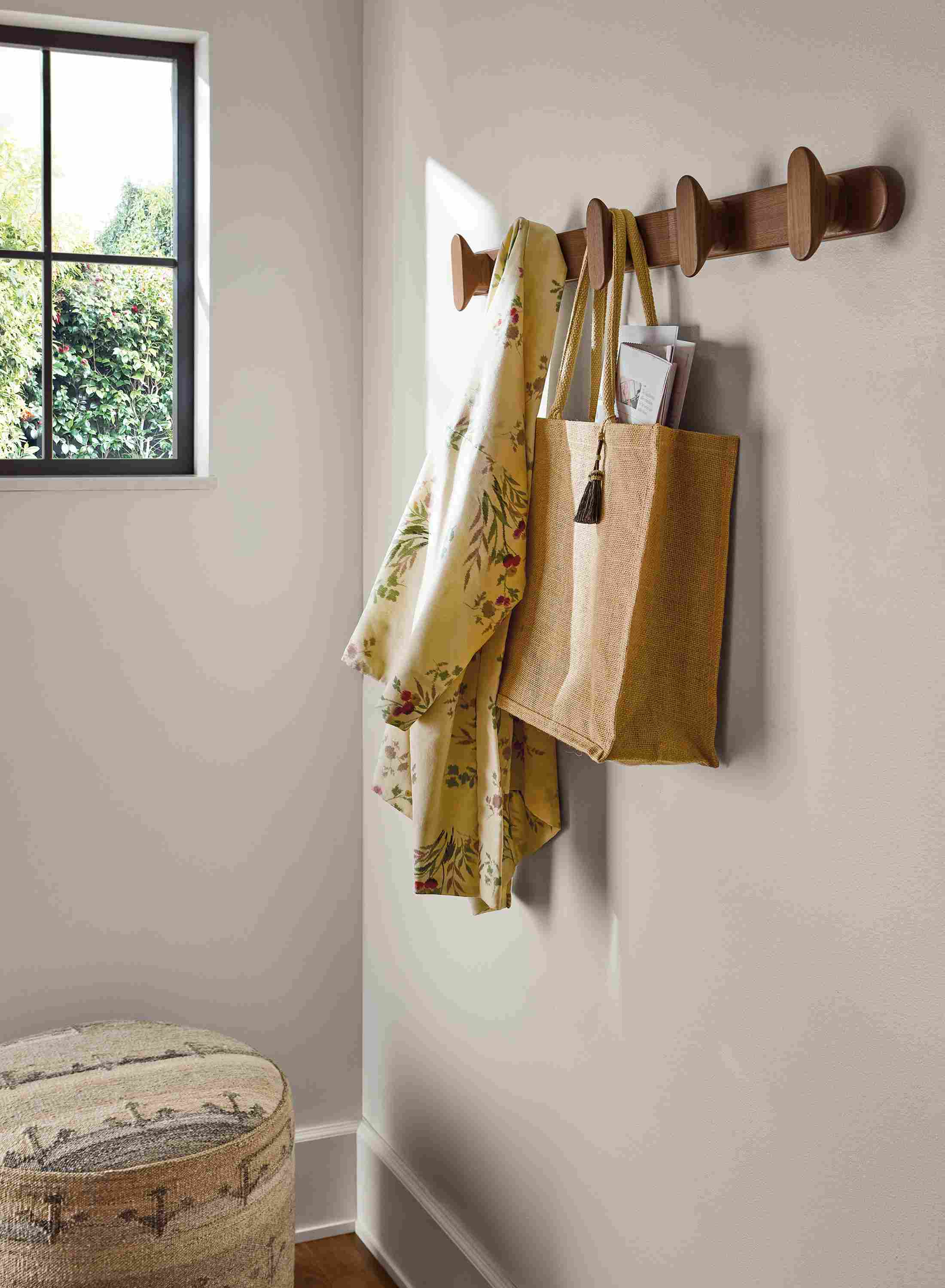 Detail of Sonora 36-wide multiple wall hook in walnut and Indira 20-diameter ottoman in Anvi Natural.