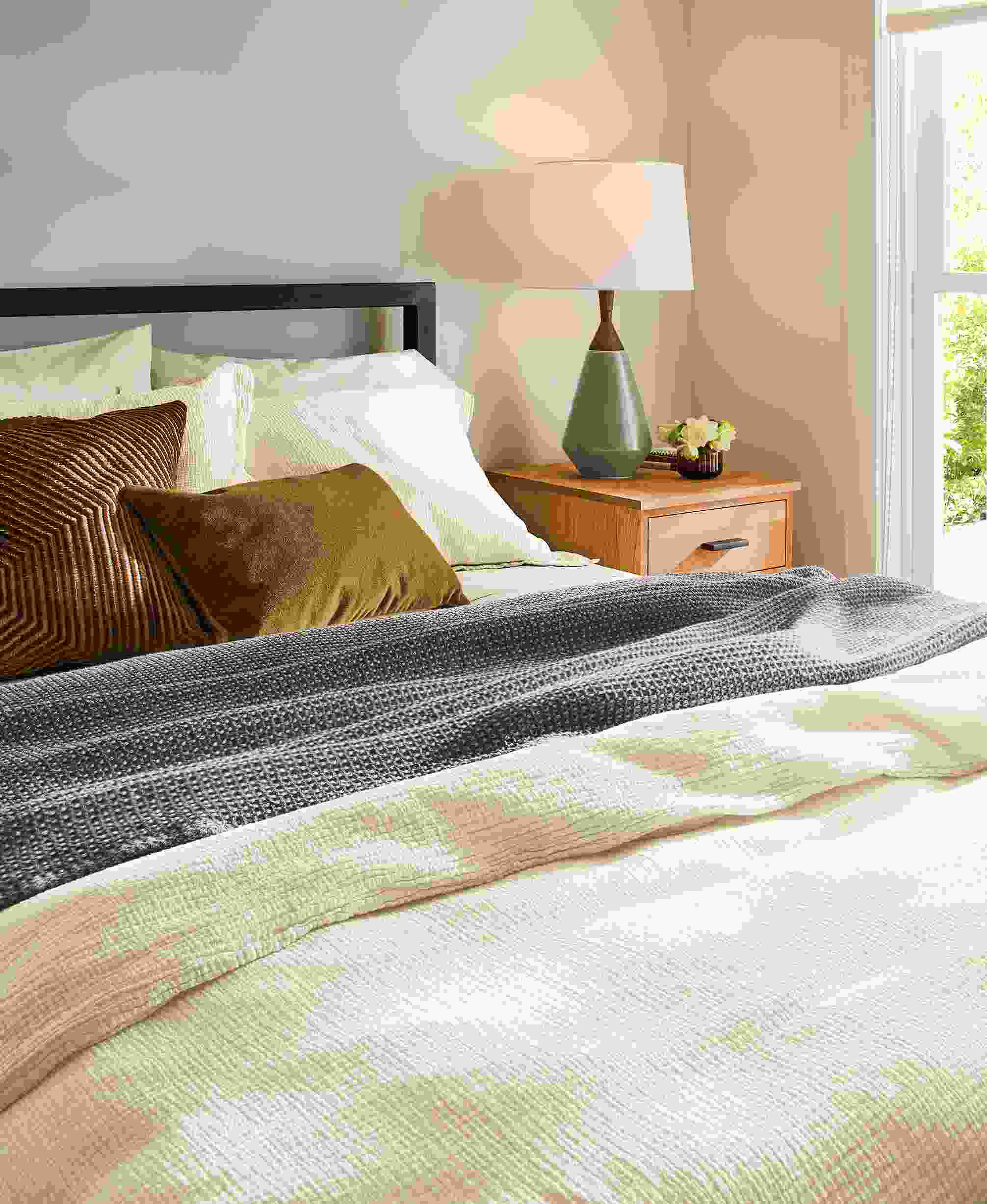 Bedroom detail of parsons bed with strand duvet set in ecru, morgan blanket in earth and signature cotton percale sheets in ecru.