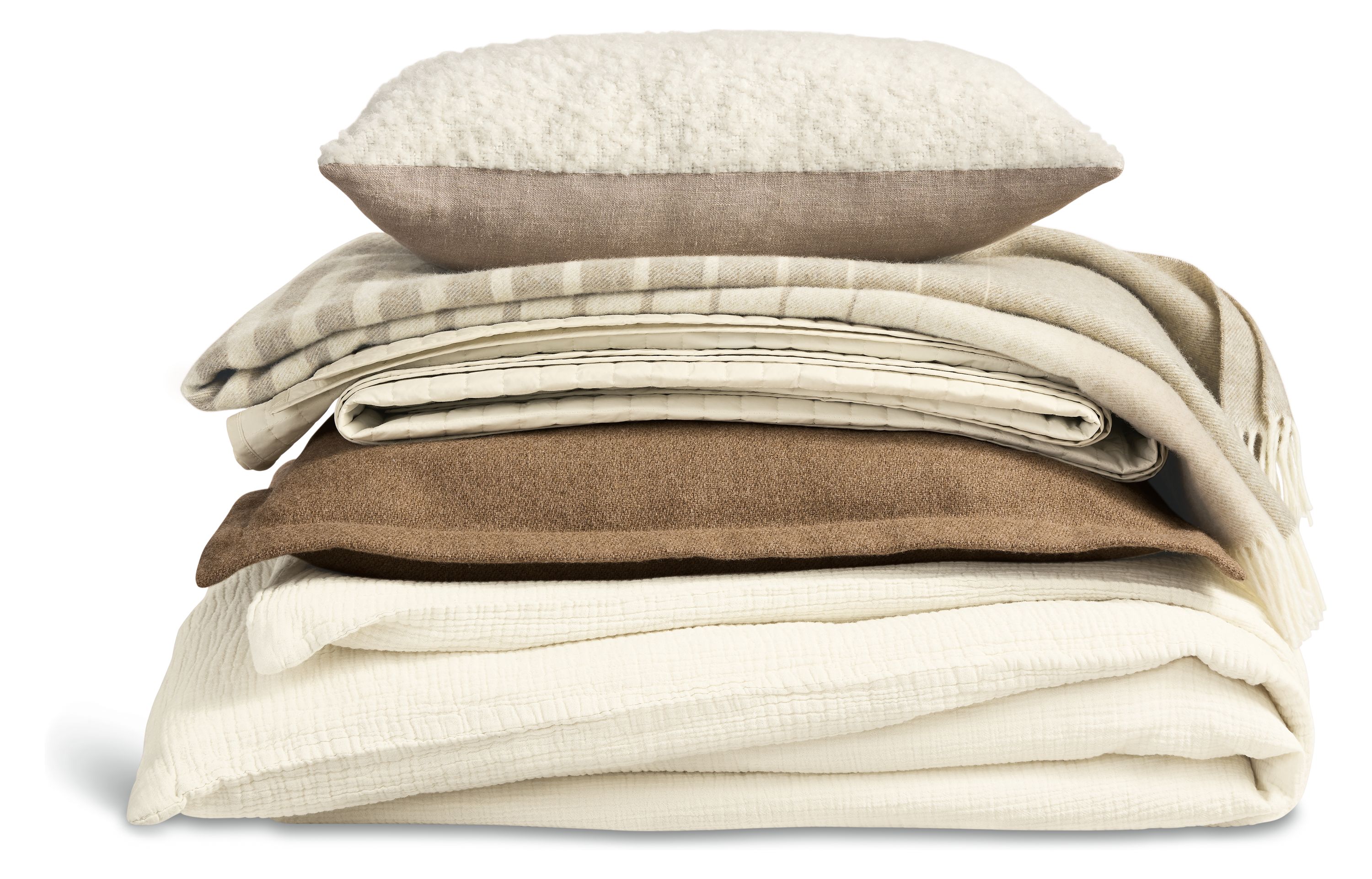 Stack of bedding with strand duvet set in ecru, washable wool euro sham in camel and percale coverlet in ecru.