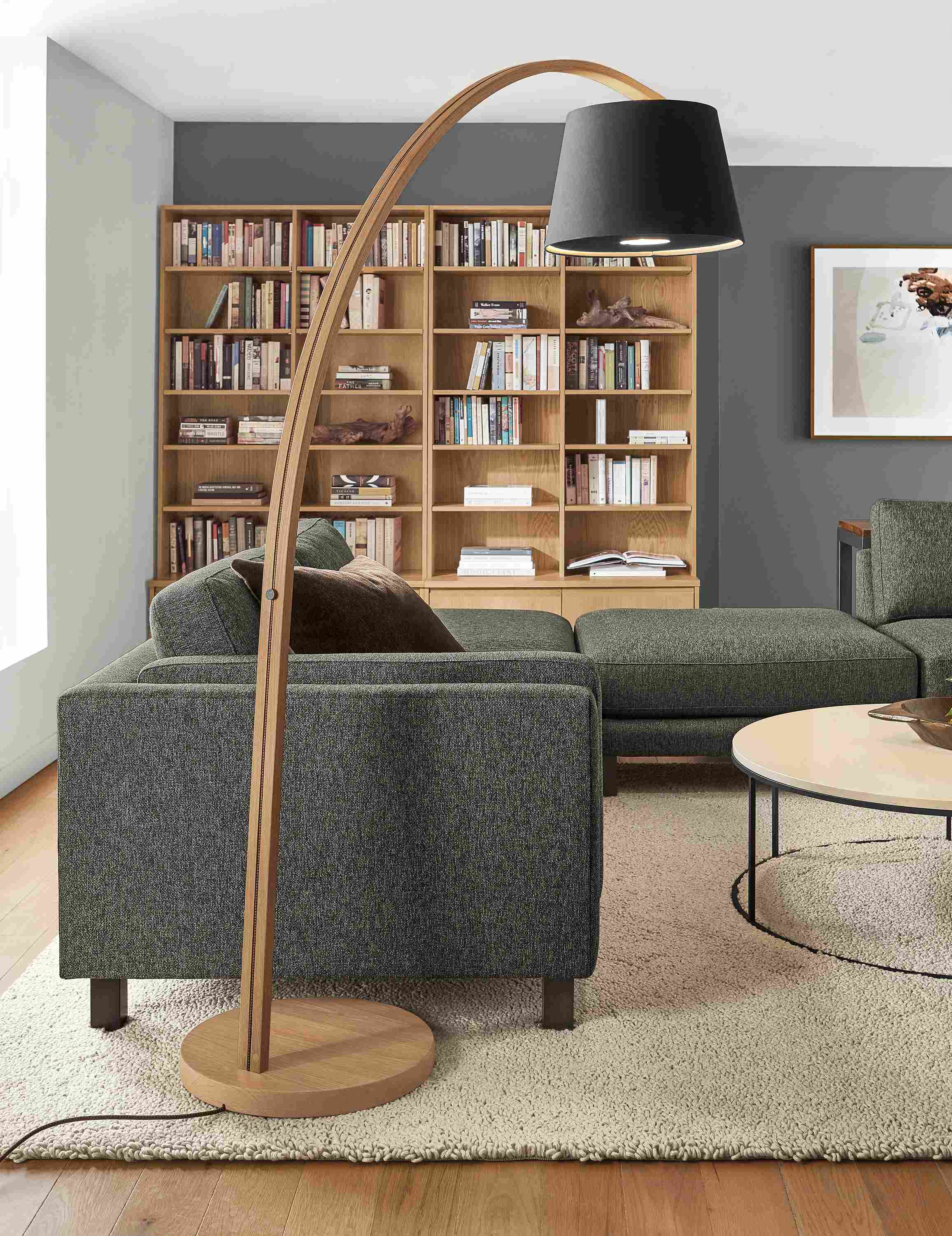 Living area with Streeter floor lamp and keaton bookcases in rye on red oak and Cade sectional in tepic charcoal fabric.