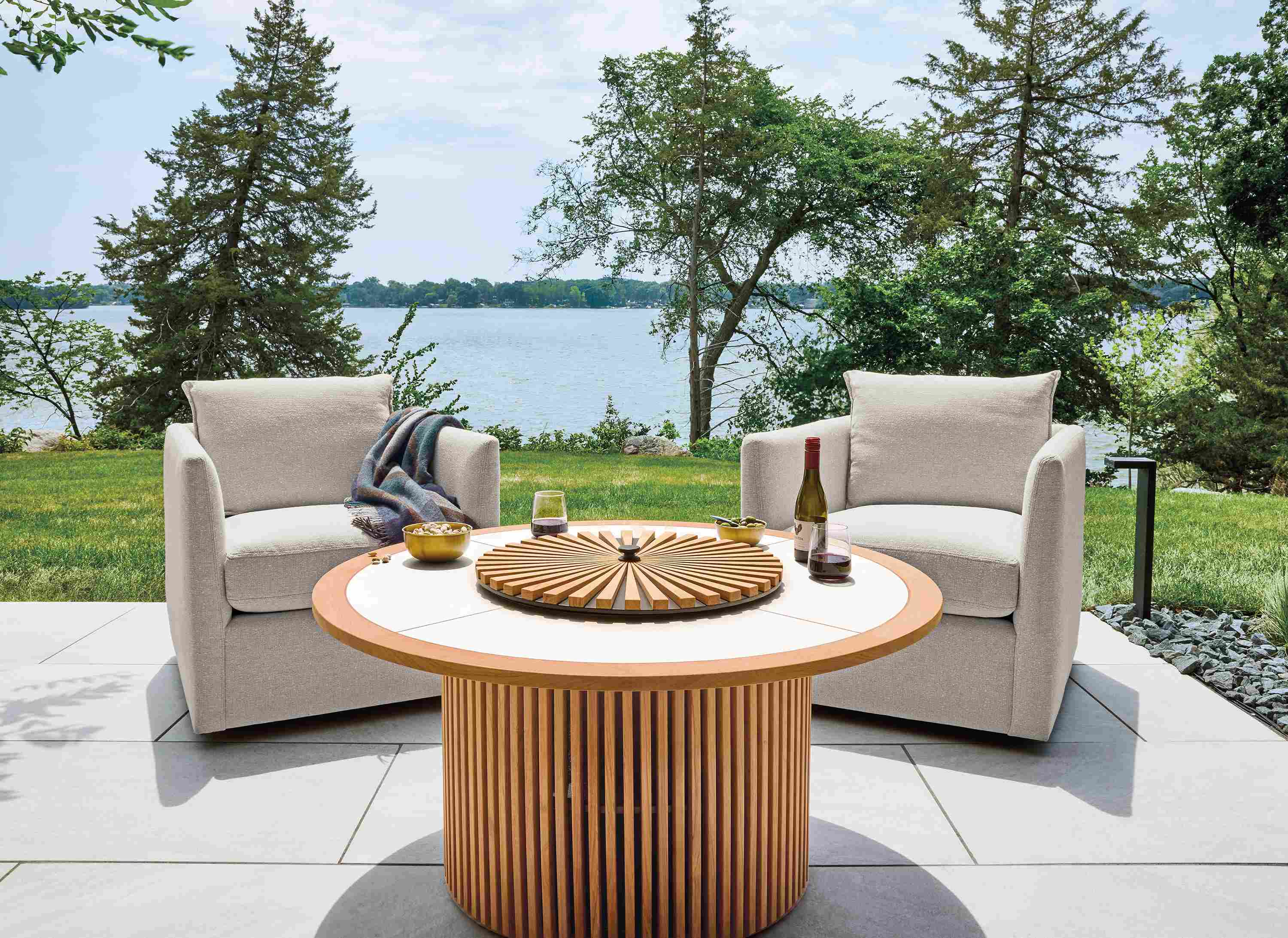 Patio with Sumba fire table in teak heartwood with winter white ceramic top shown with cover in place.