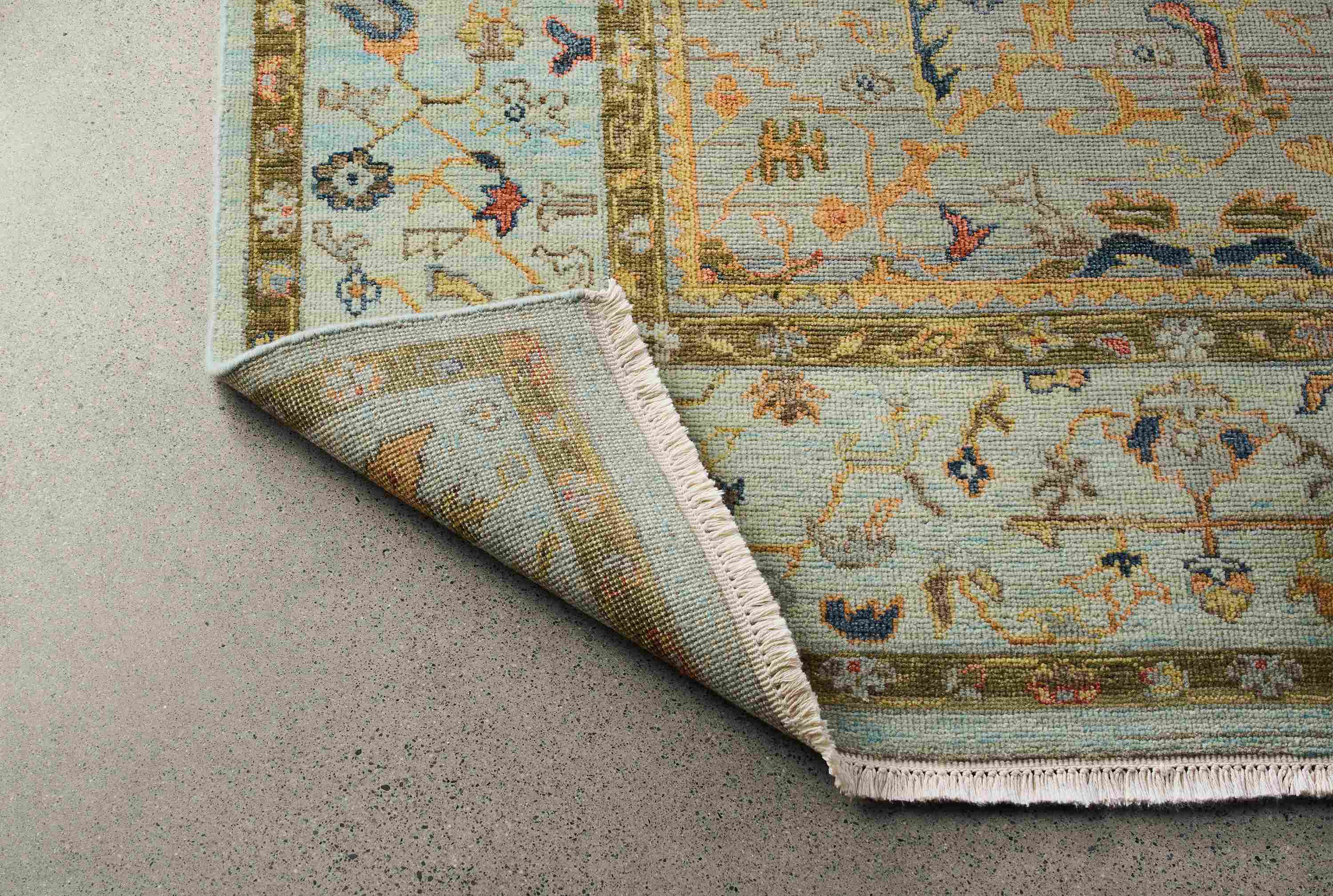 Detail of an upturned corner showing the back on a sundar 8 by 10 rug in sky.