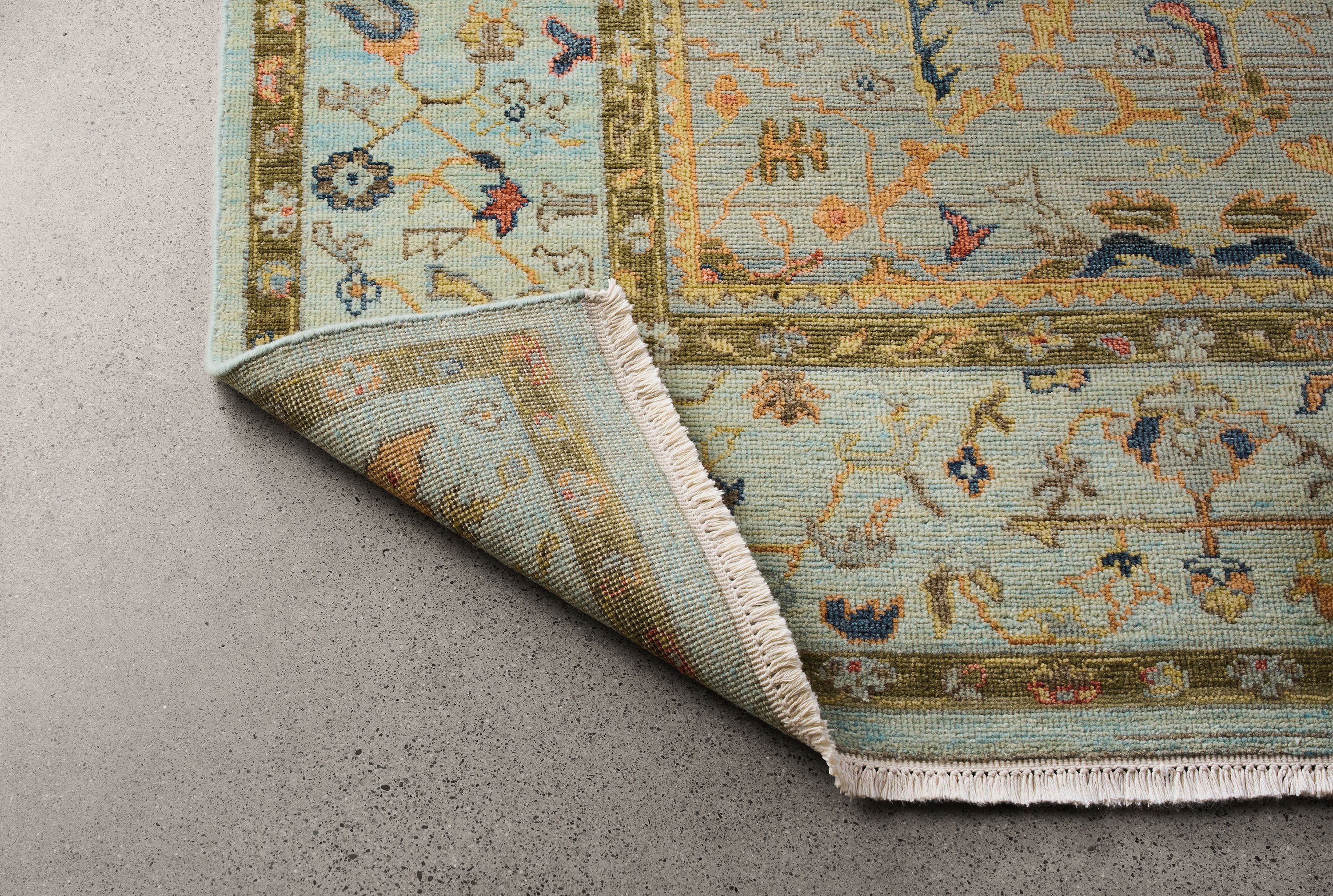 Detail of an upturned corner showing the back on a sundar 8 by 10 rug in sky.