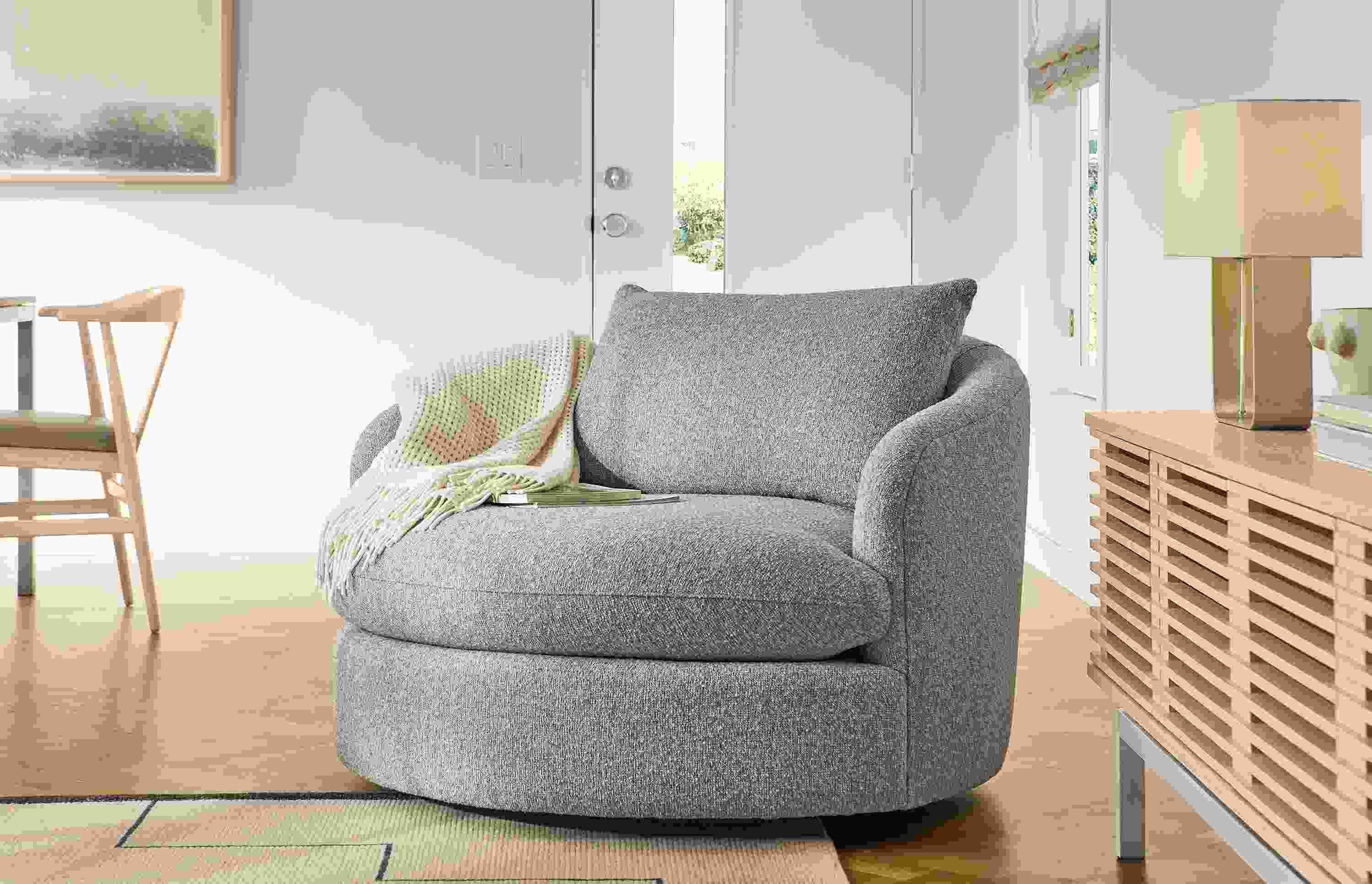 Living room with Suri swivel chair in Conley Grey, Coles media cabinet in salt on red oak and Navi rug in ivory/black.