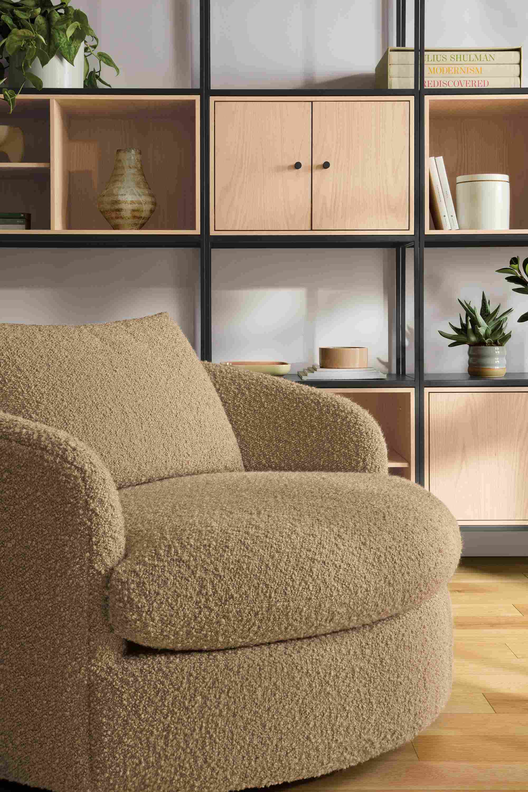 Living room with suri swivel chair in dornick camel, slim shelves in natural steel with salt inserts.