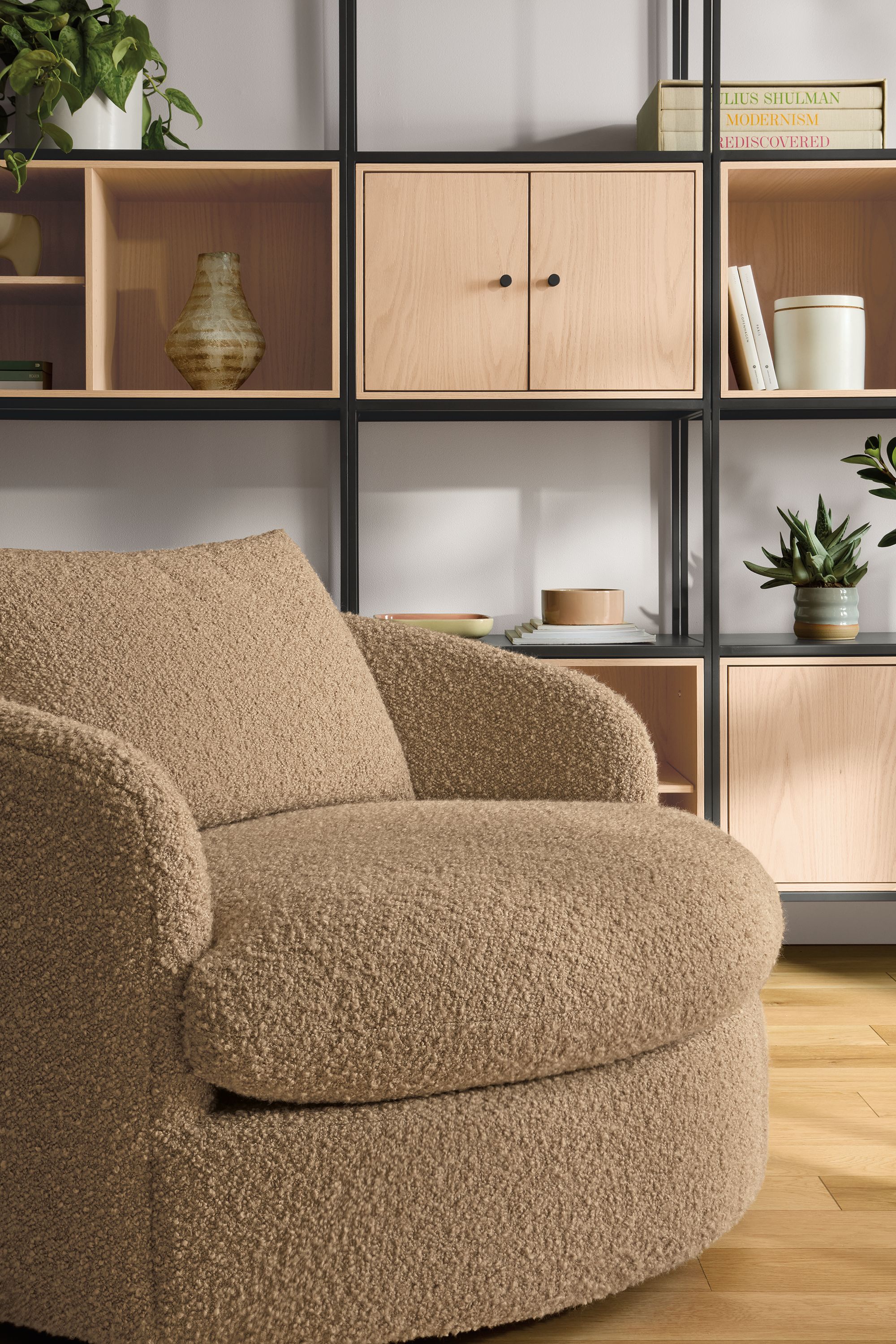 Living room with suri swivel chair in dornick camel, slim shelves in natural steel with salt inserts.