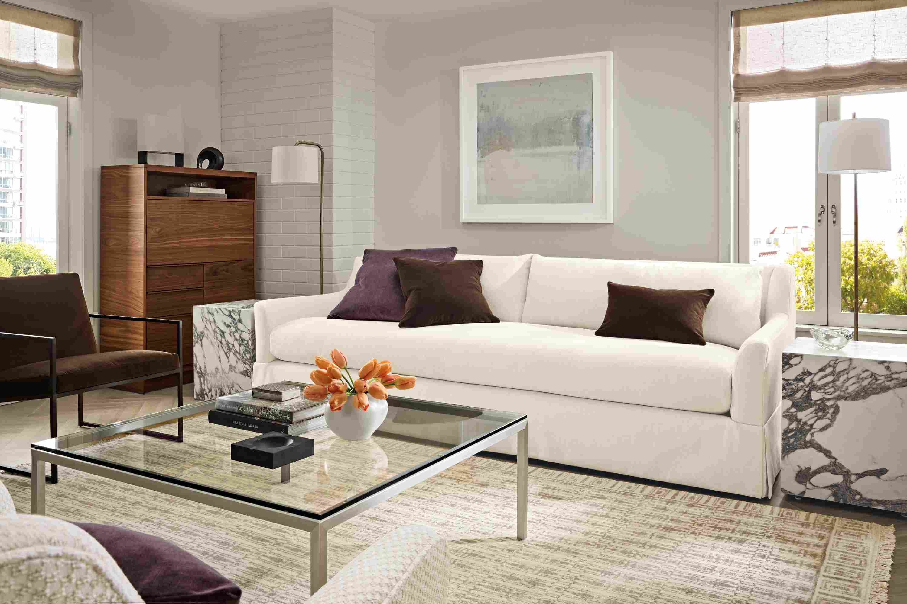 Living room with Sybil 100-wide bench cushion sofa in Sumner Ivory, Parsons coffee table in stainless and clear glass.