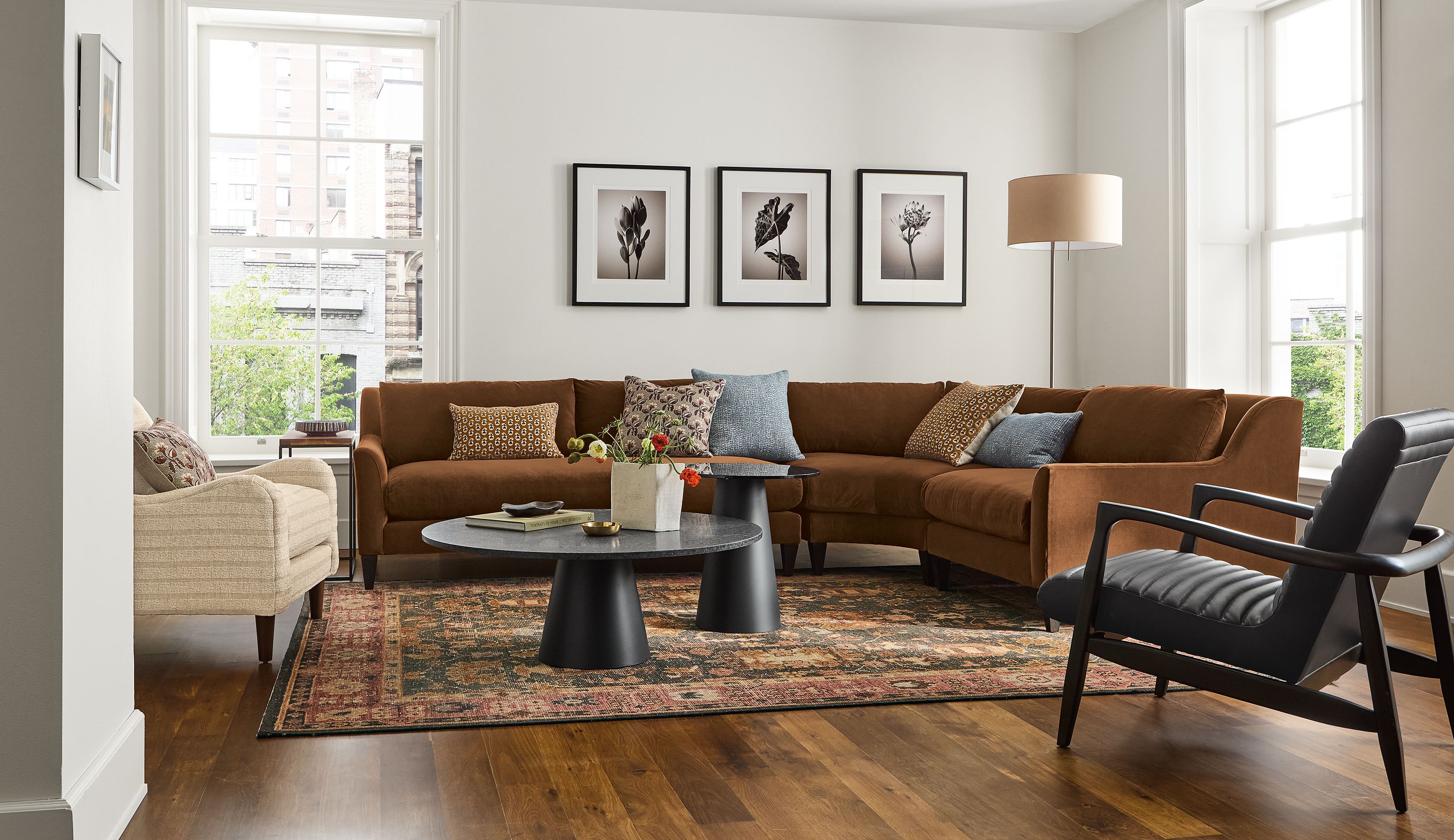 Living room with Sybil 3-piece curved sectional in redding nutmeg, eloise chair in auckland natural and Callan chair in Pesaro black leather.