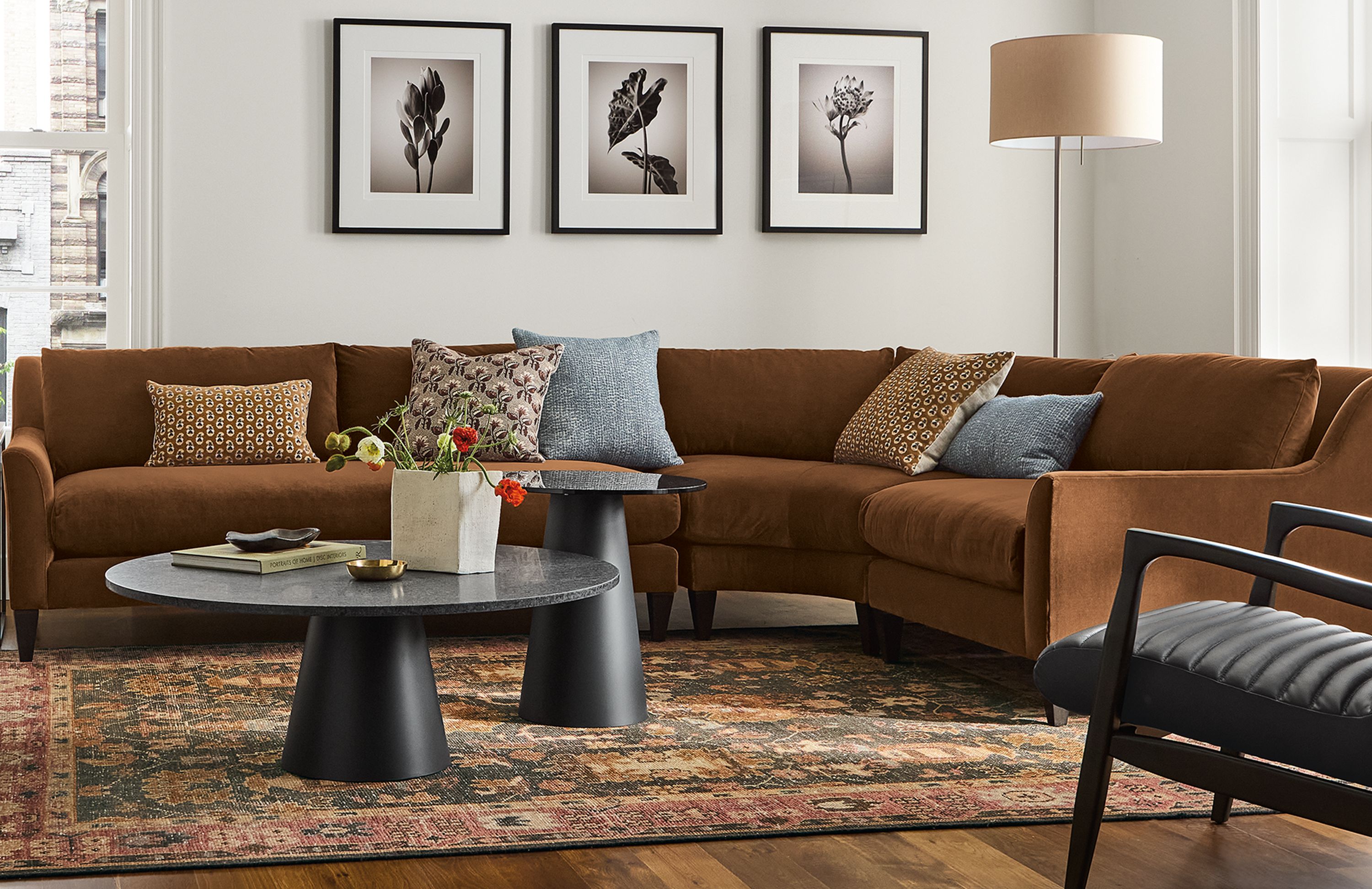 Living room with Sybil 3-piece curved sectional in redding nutmeg, eloise chair in auckland natural and Callan chair in Pesaro black leather.