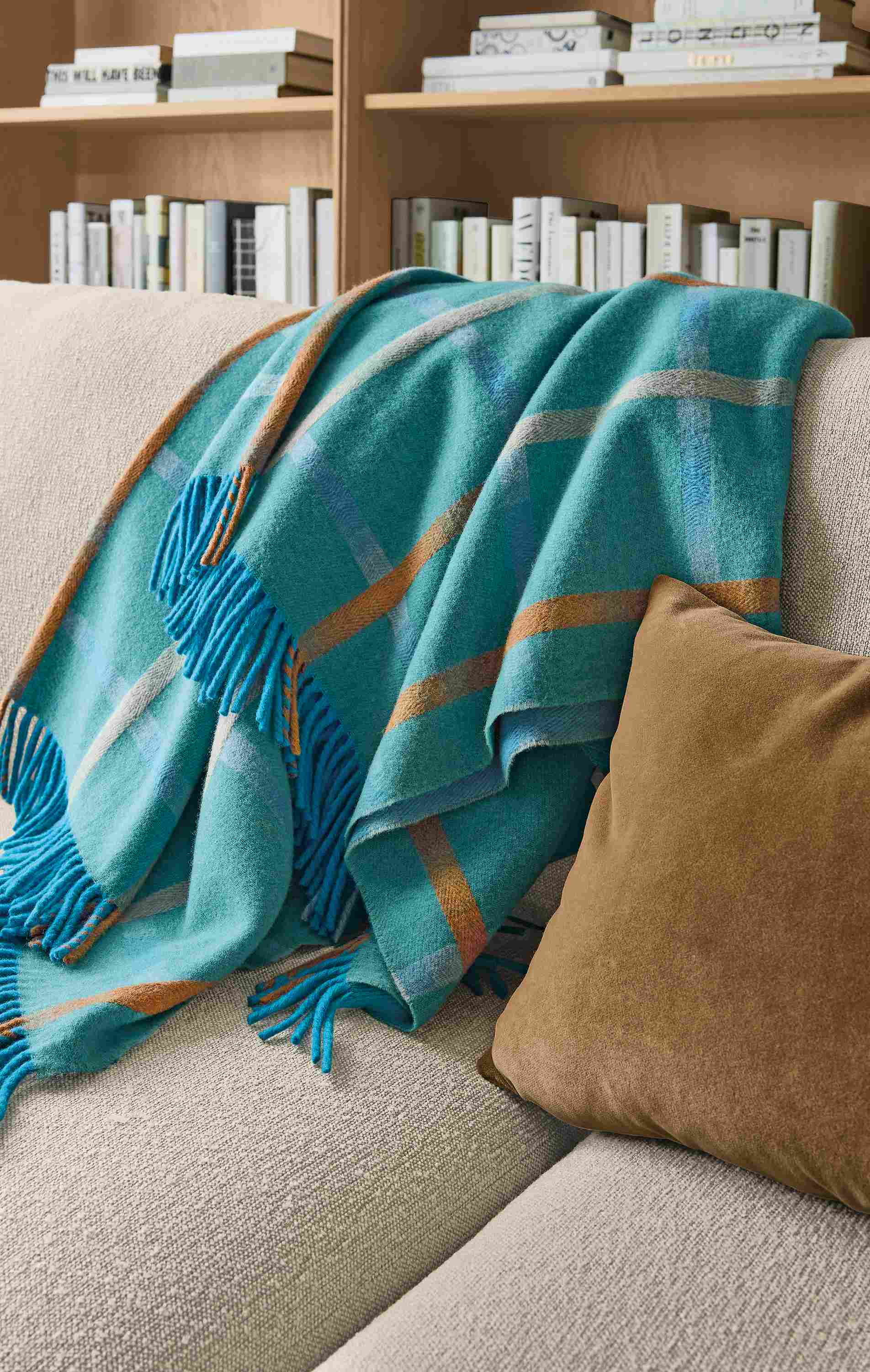 Tahoe throw blanket in peacock draped over a fia sofa in conley natural and velvet throw pillow in camel.
