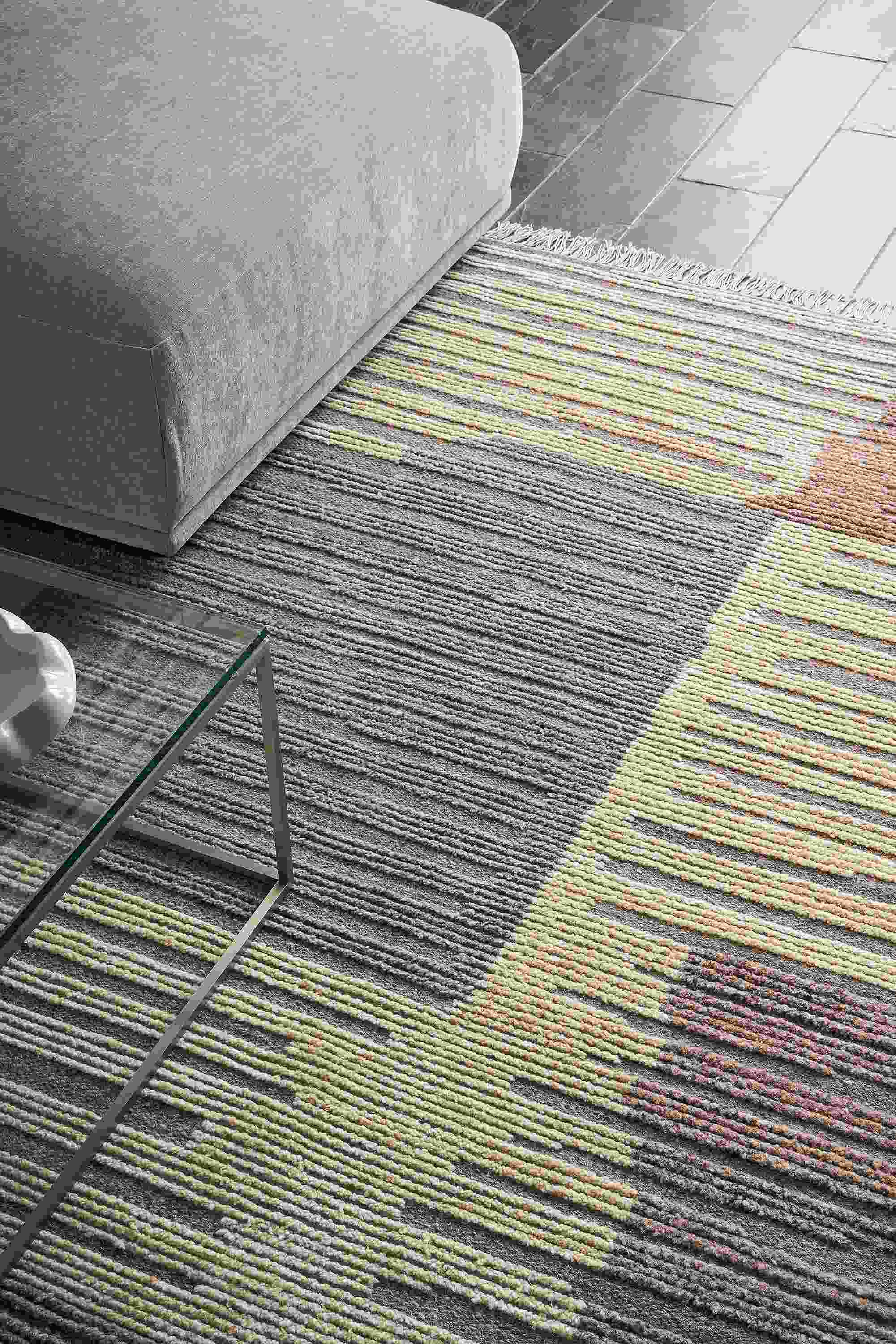 Room with detail of tangier 8 by 10 rug in natural, fia sofa in mori cement and tyne coffee table in clear glass and stainless steel.