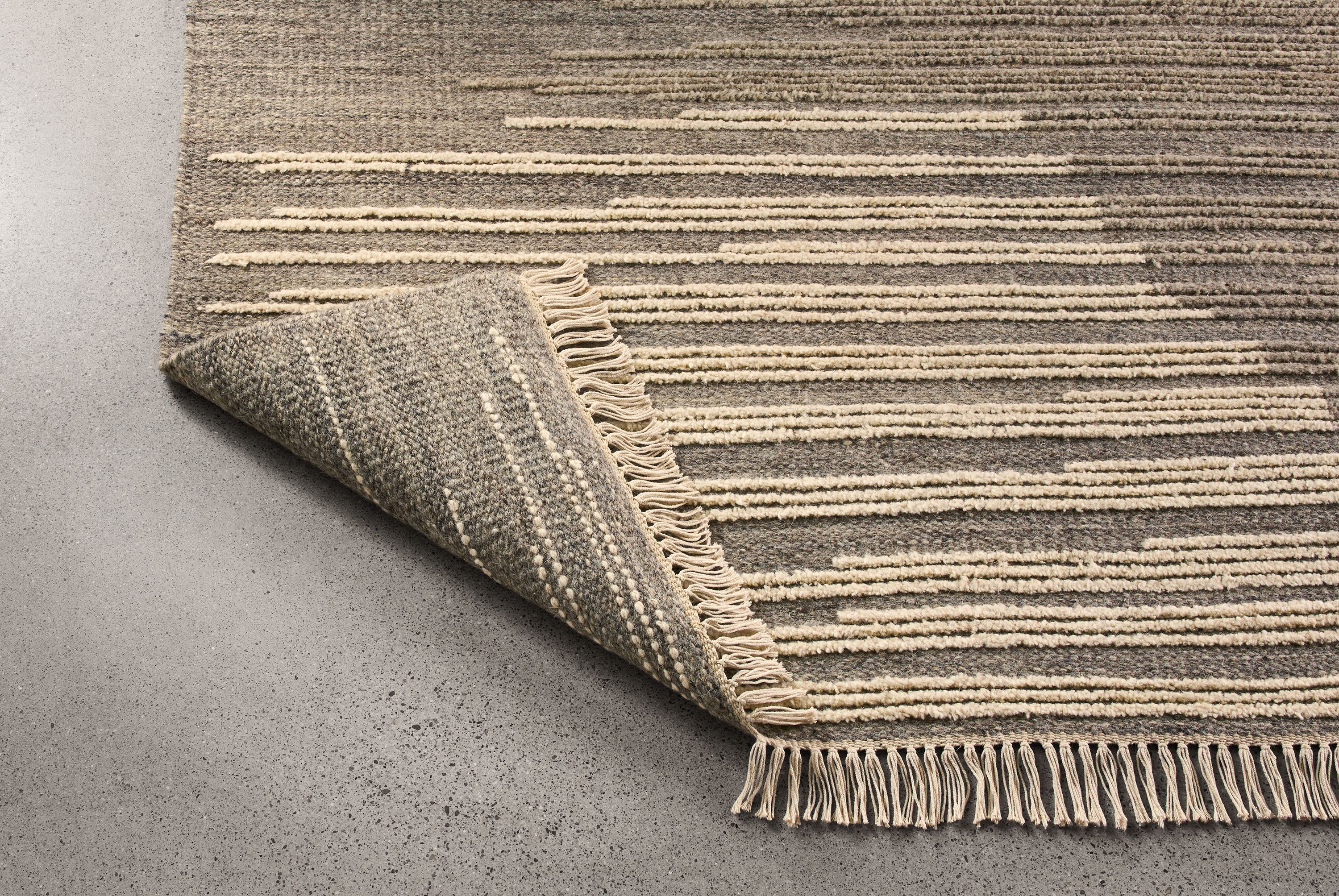 Tangier 8 by 10 rug in natural shown with corner flipped up to show underside of rug.
