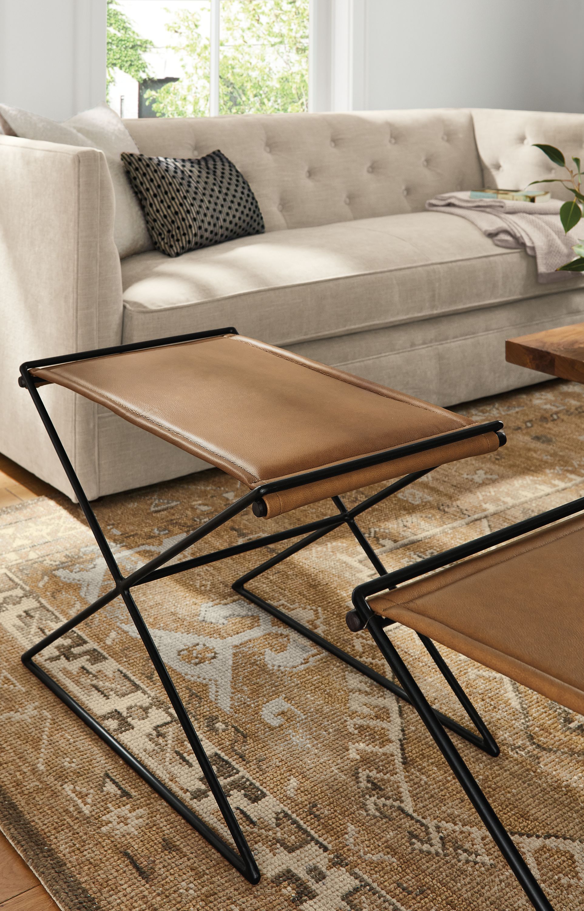 living room with two tavi stools in leather on darrah rug.