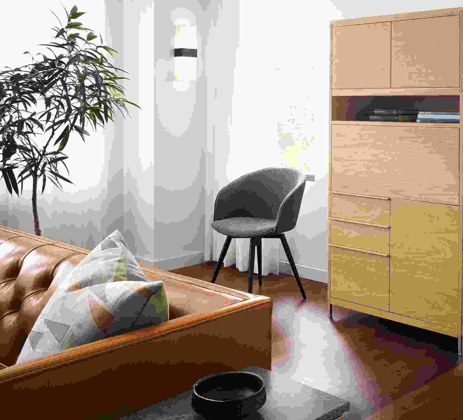Living room with Taylor office wall unit in white oat and Sylvan swivel side chair in Radford Grey with graphite legs.