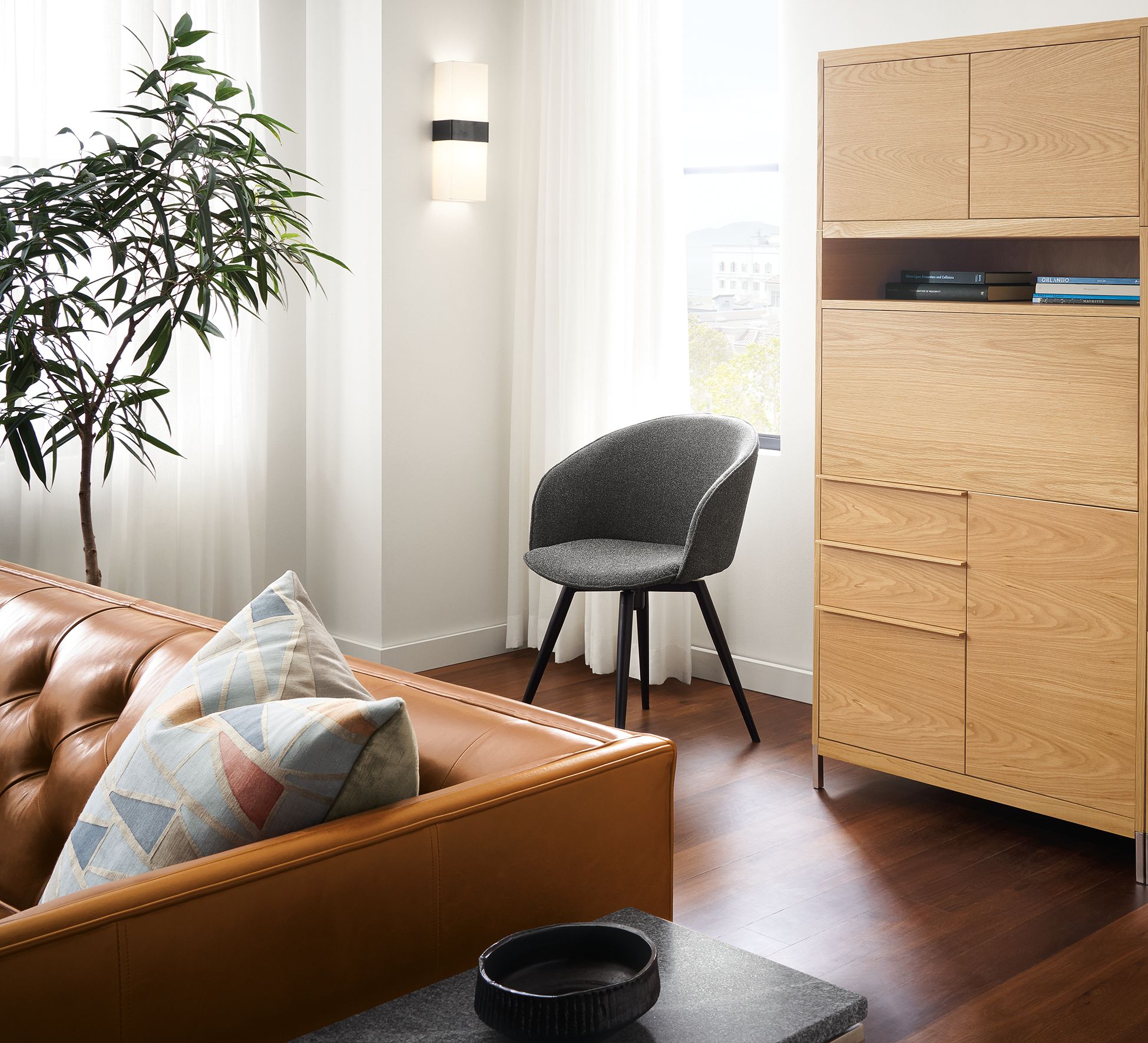 Living room with Taylor office wall unit in white oat and Sylvan swivel side chair in Radford Grey with graphite legs.