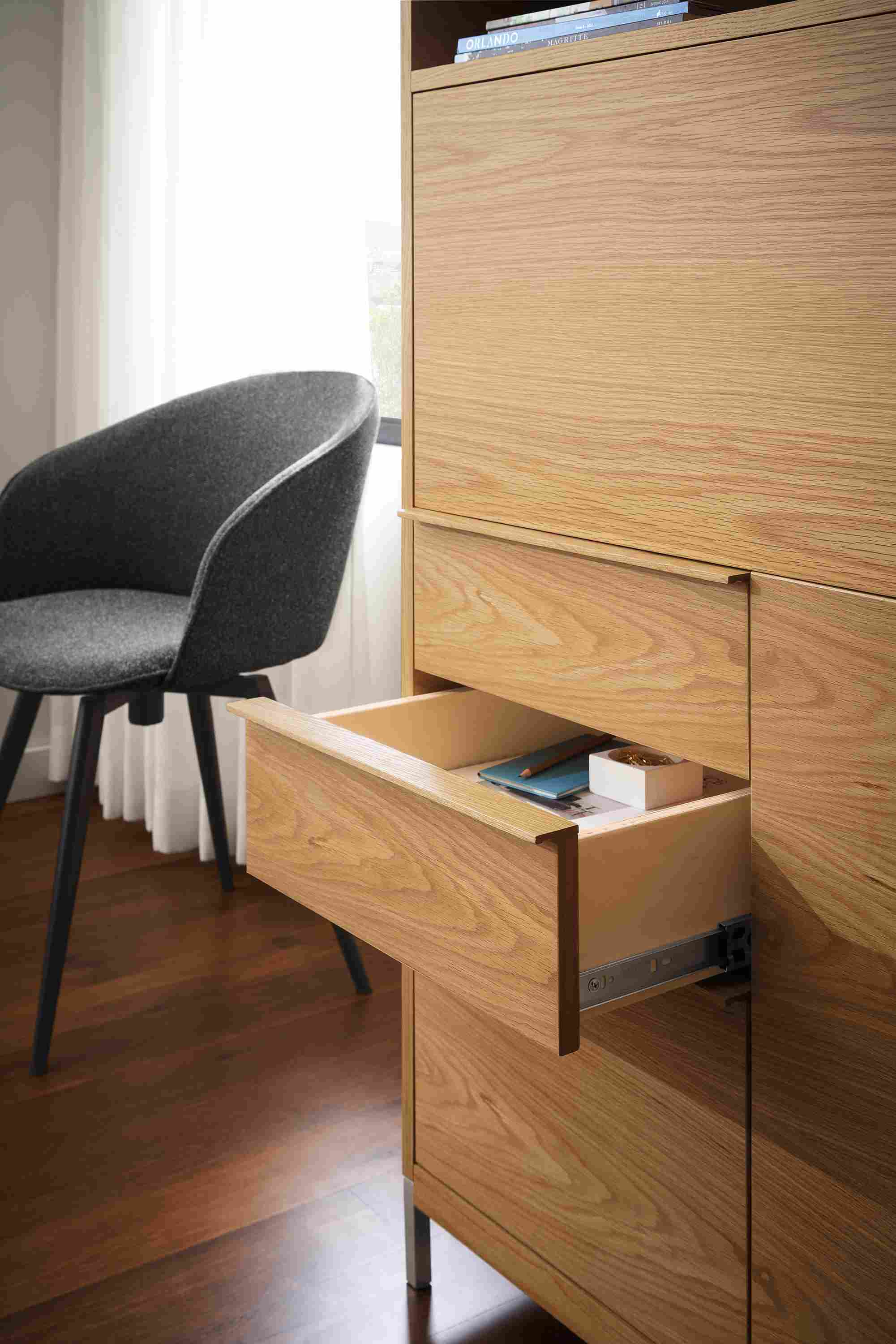 Detail of open drawer of Taylor office wall unit in white oak and Sylvan swivel side chair in Radford Grey and graphite.