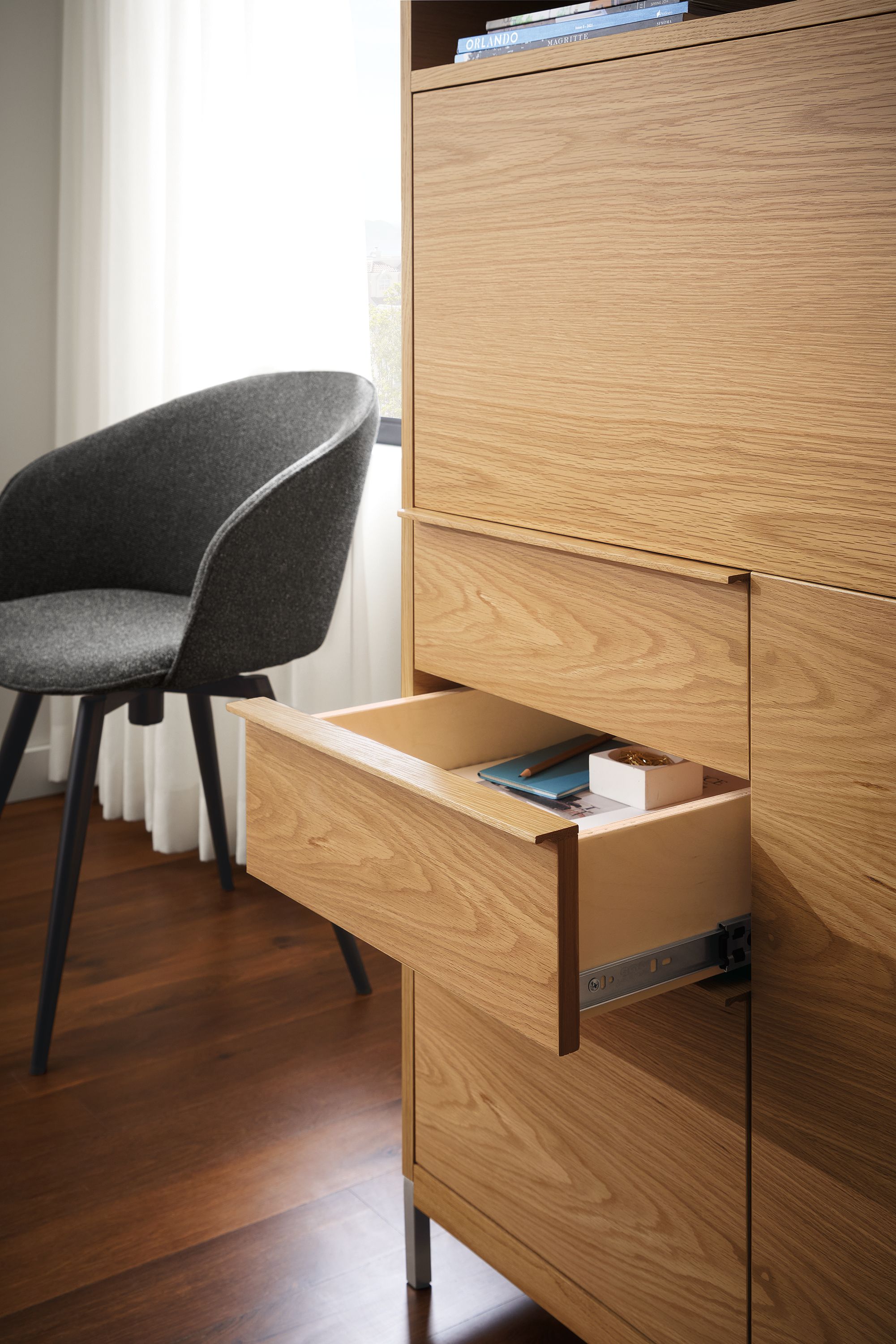Detail of open drawer of Taylor office wall unit in white oak and Sylvan swivel side chair in Radford Grey and graphite.