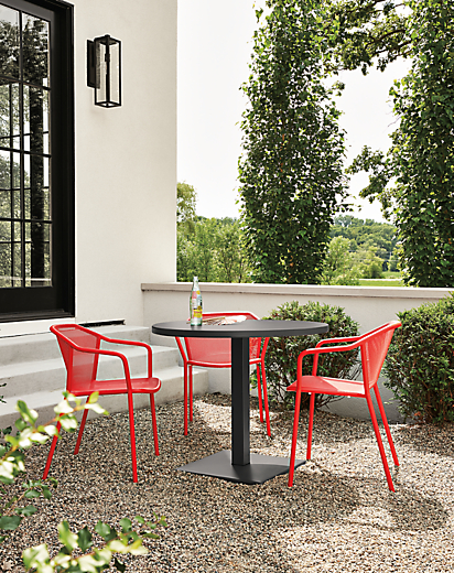 Detail of red Theo chairs and Maris round table on patio.