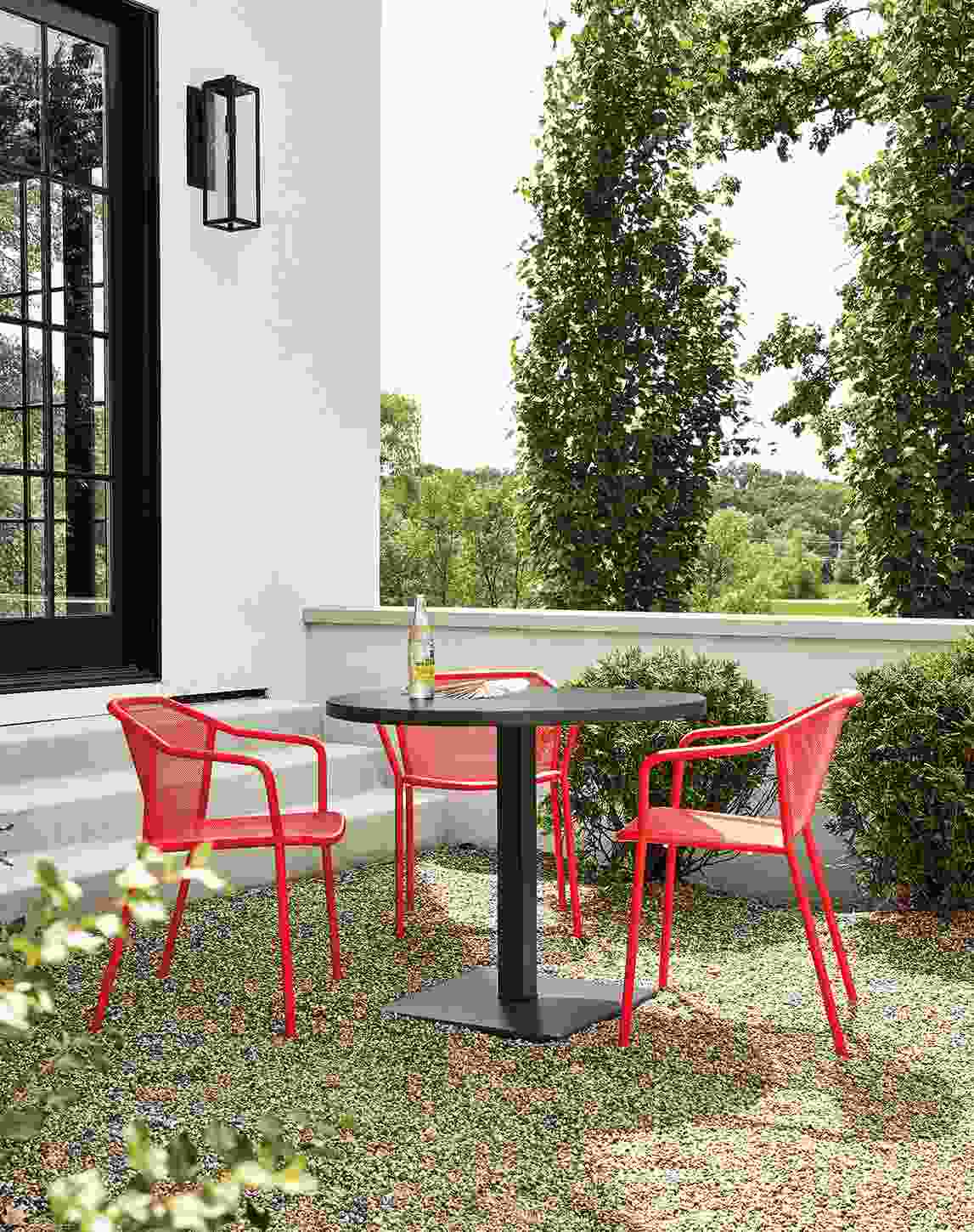 Detail of red Theo chairs and Maris round table on patio.