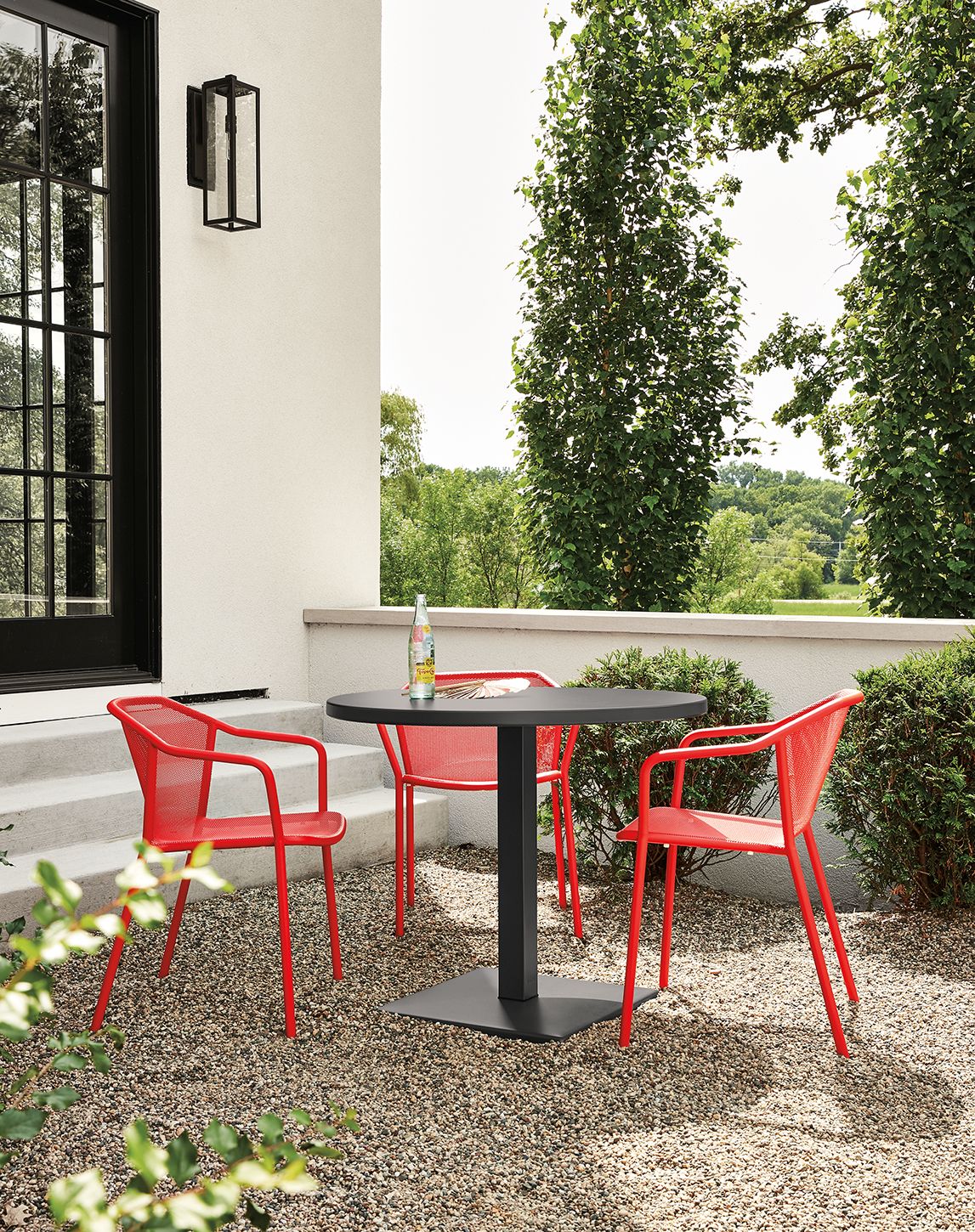 Detail of red Theo chairs and Maris round table on patio.