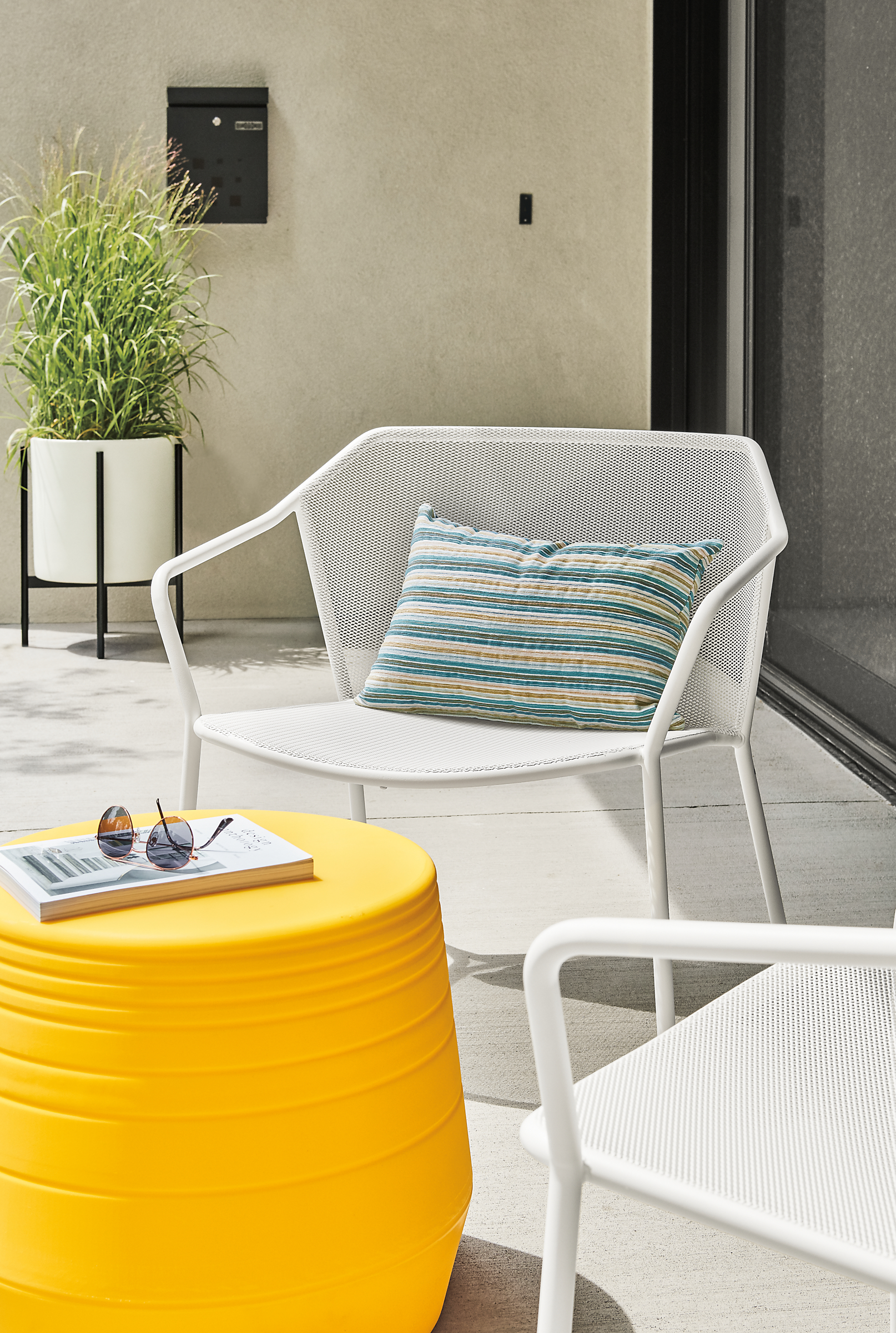 Detail of Theo outdoor lounge chair in white with Sunset pillow.