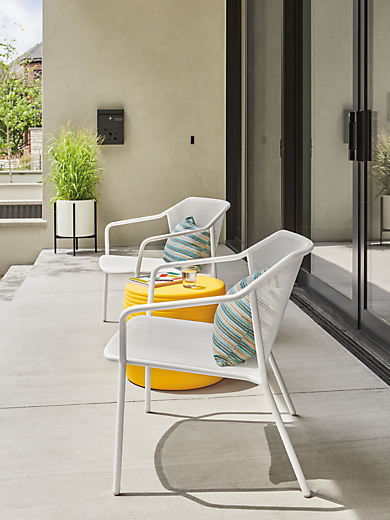 Detail of two Theo lounge chairs in white and Cusp round stool in yellow.