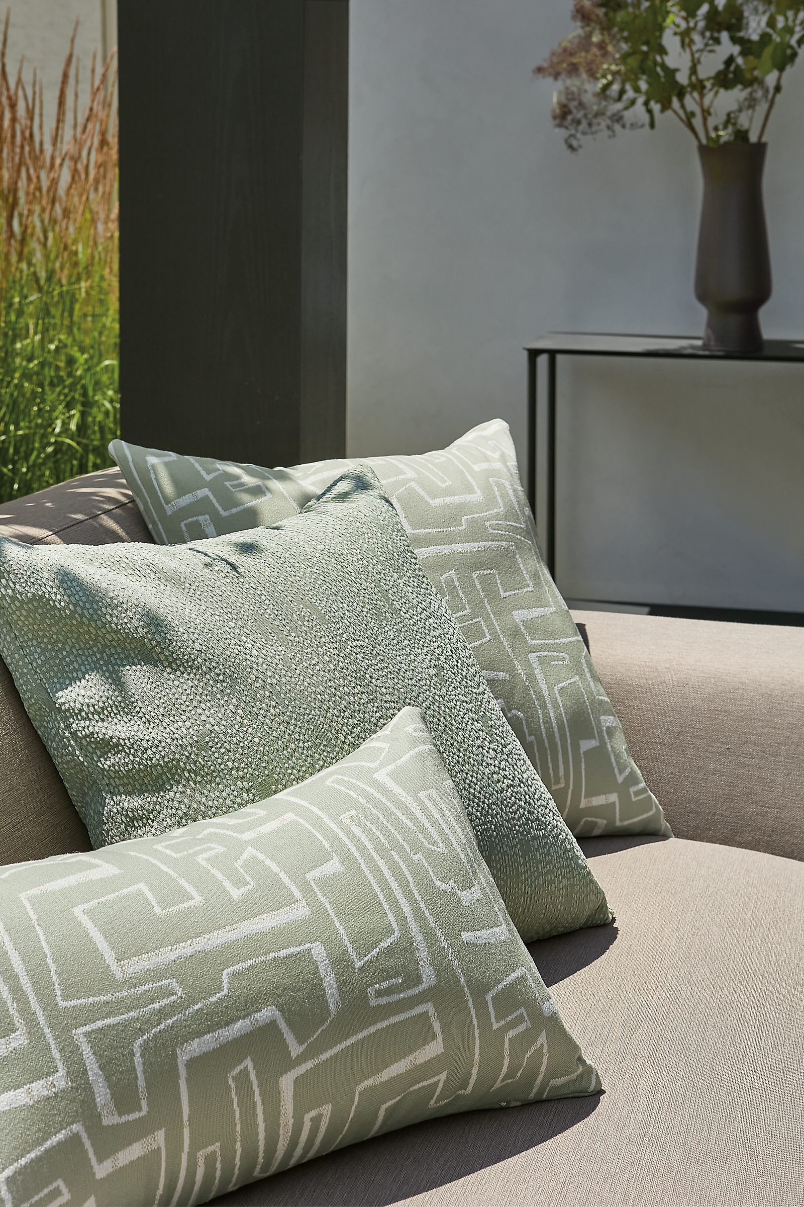 Outdoor space with several green outdoor pillows on drift sofa.