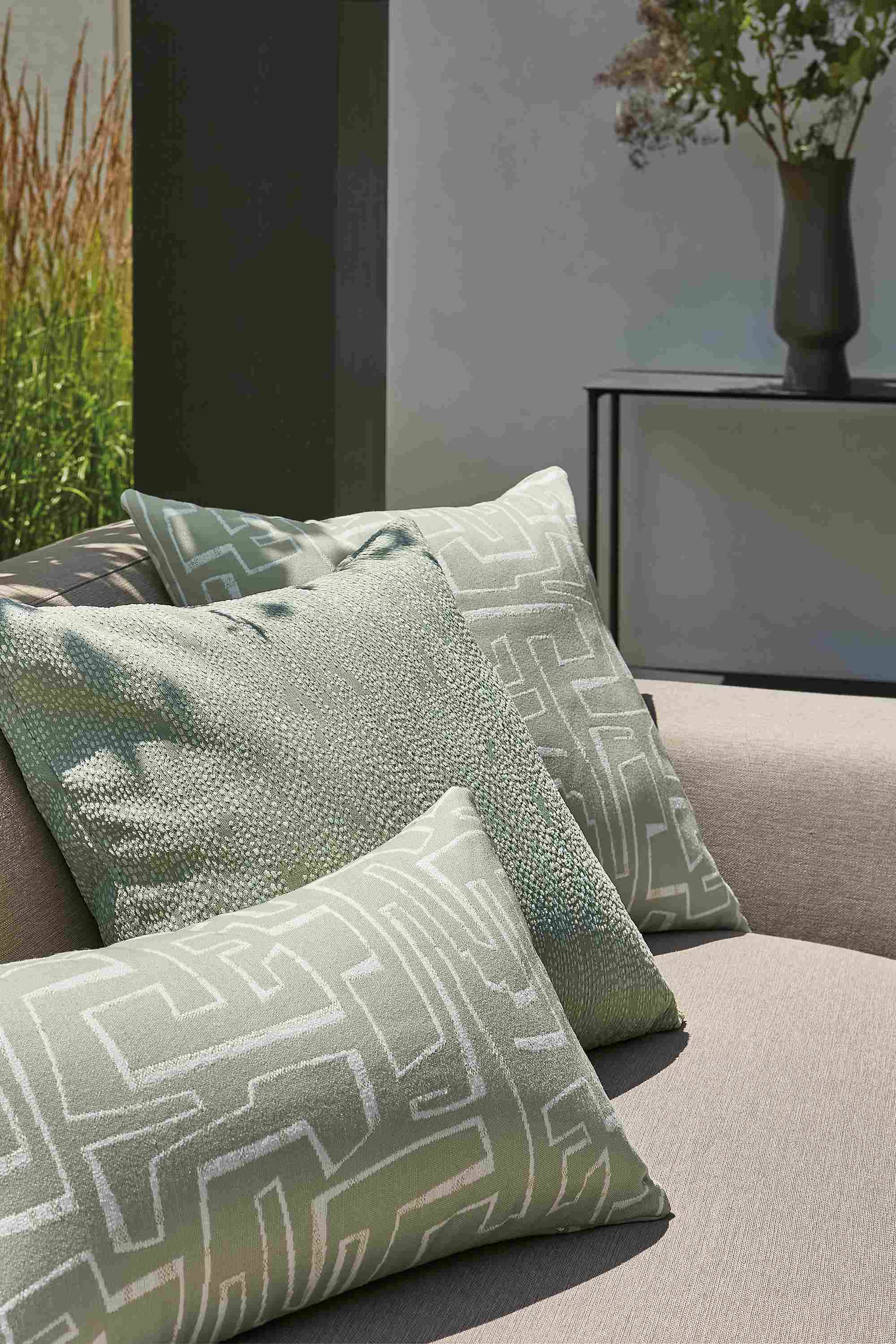 Outdoor space with several green outdoor pillows on drift sofa.