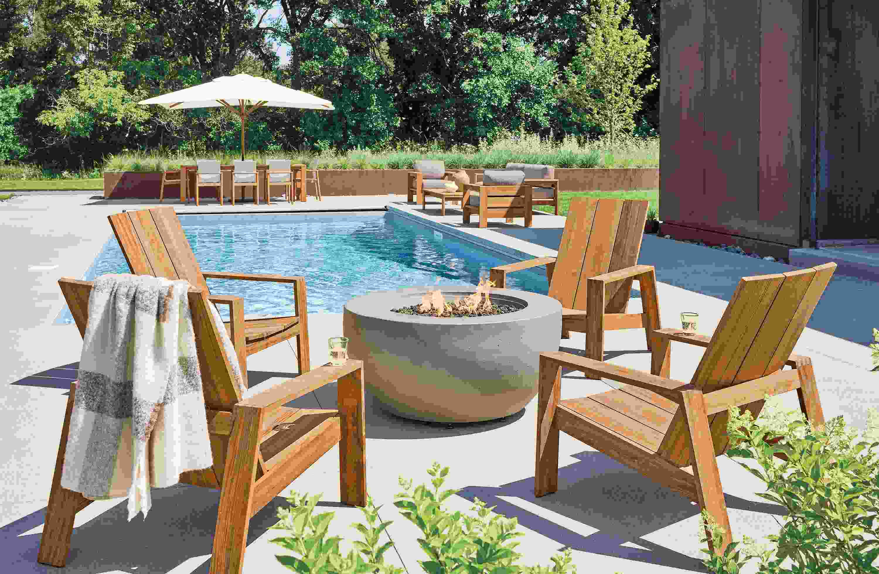 Pool patio with 4 Timor lounge chairs in Doreng Teak Heartwood and Pele propane fire table in grey.