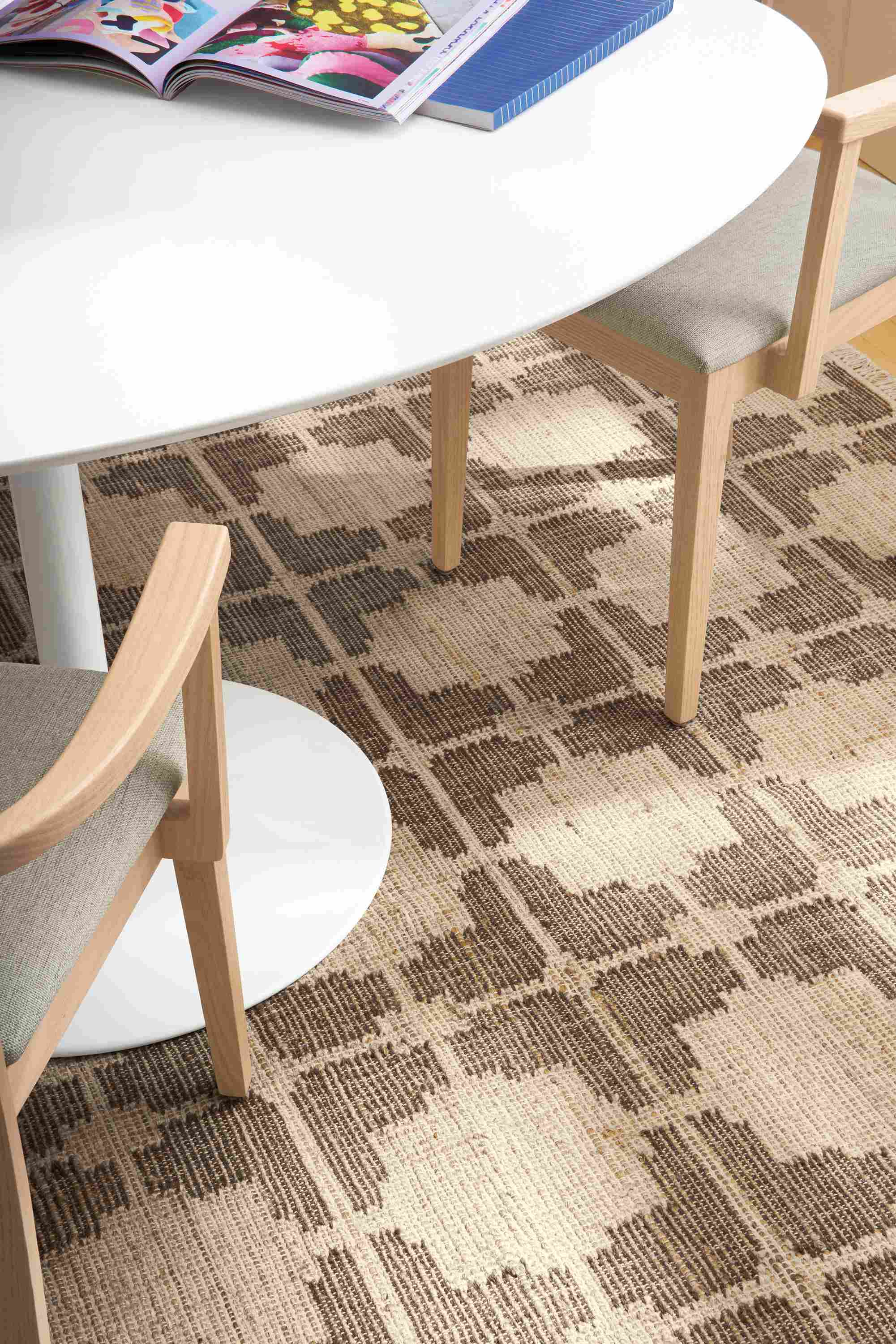 Detail of Tinsley 6 by 9 rug in putty with Aria oval table in white and 2 Doyle arm chairs.