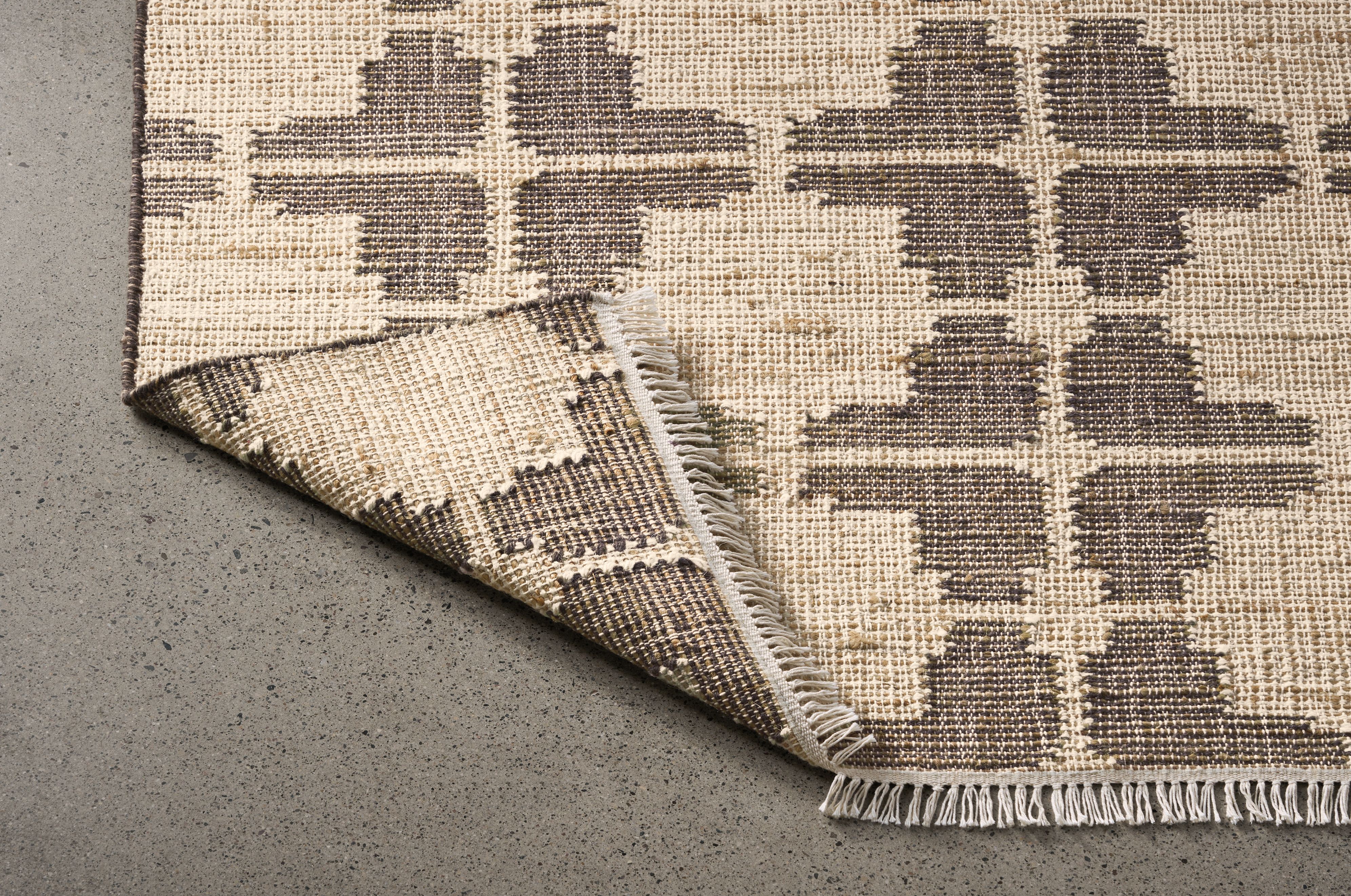 Detail of a Tinsley 8 by 10 rug in putty with corner folded to show underside of rug.