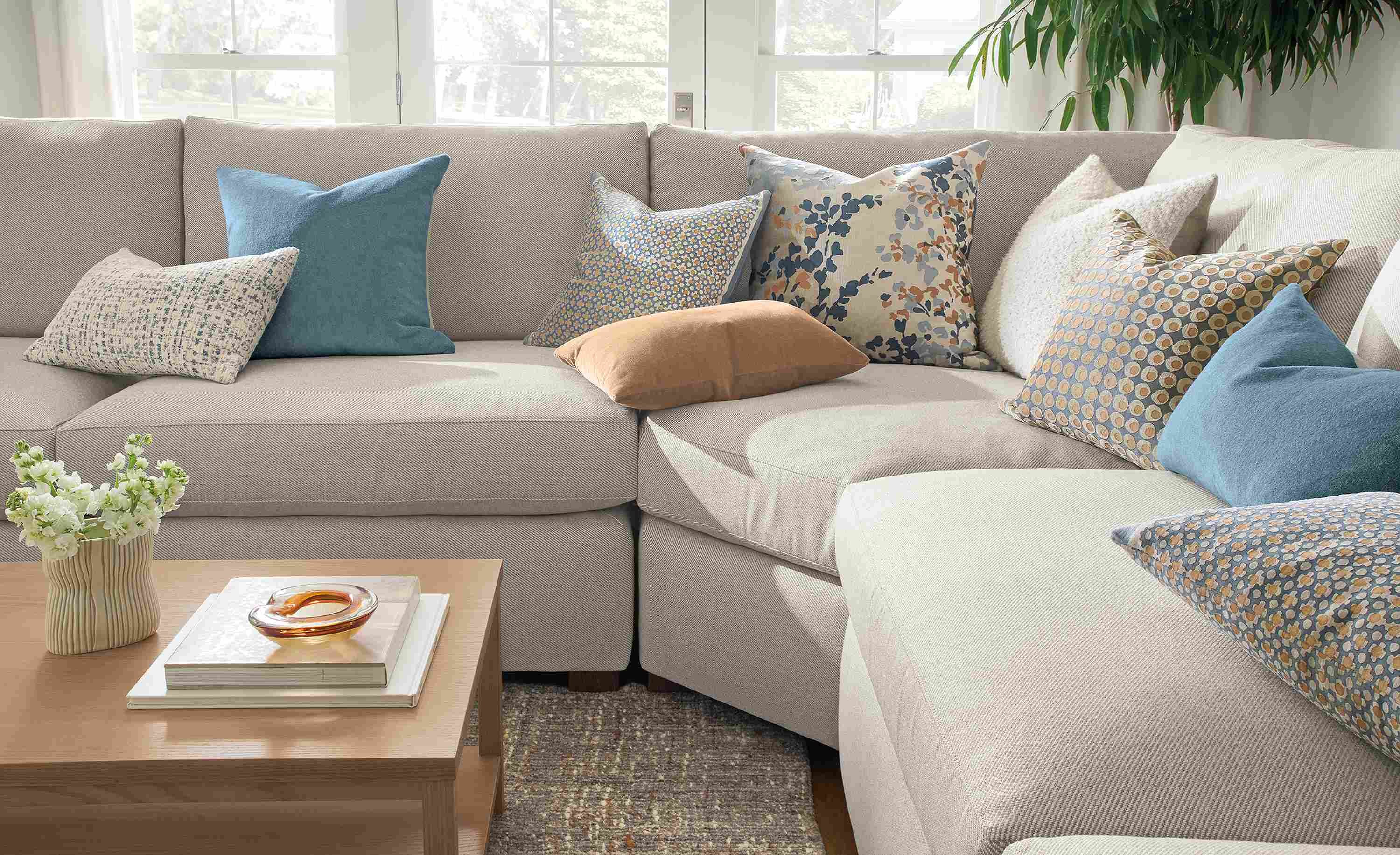 Living room with various pillows including Tromso, wool velvet, Filigree, Windsor velvet and Fleur on a Ryan sofa.