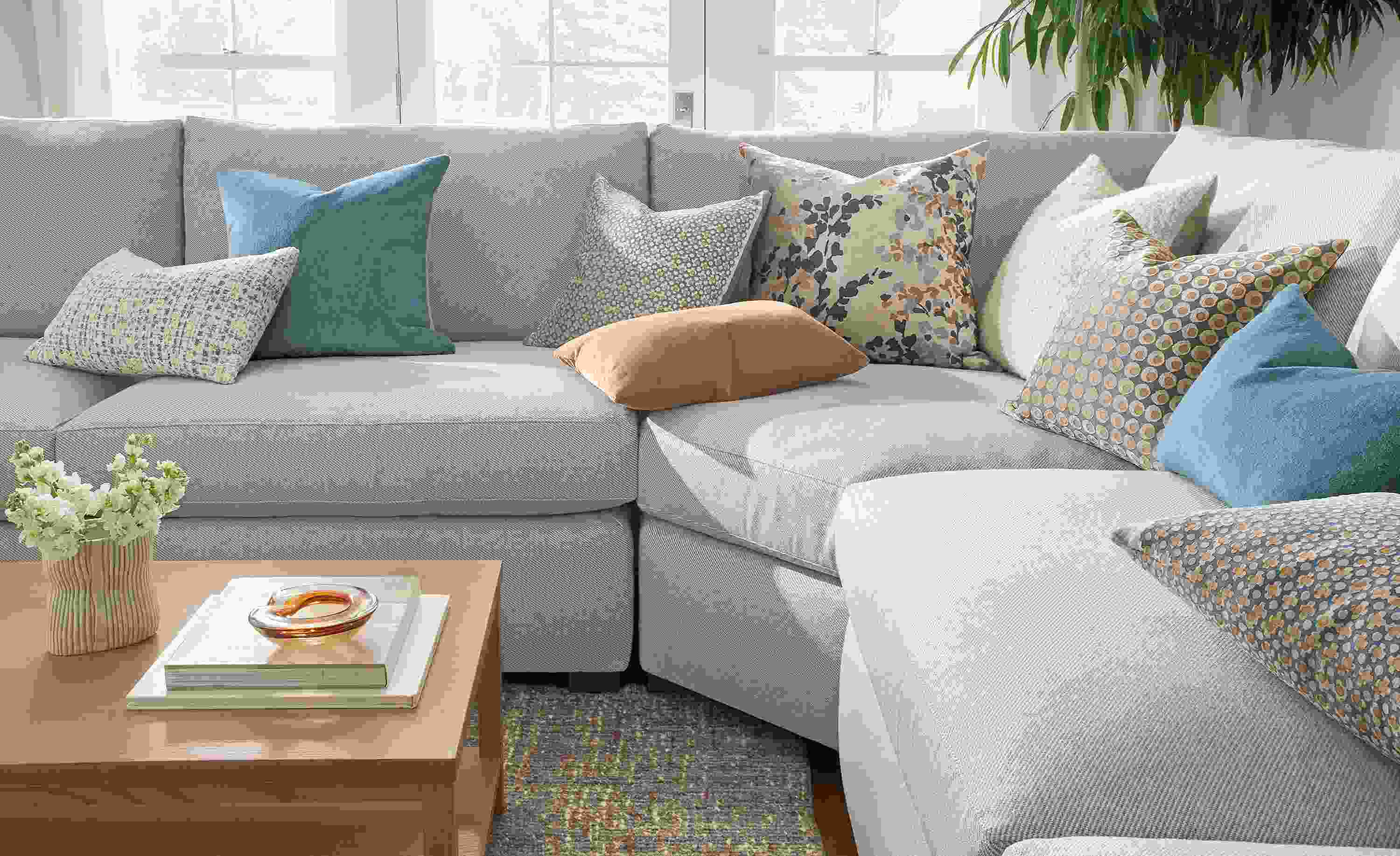 Living room with various pillows including Tromso, wool velvet, Filigree, Windsor velvet and Fleur on a Ryan sofa.