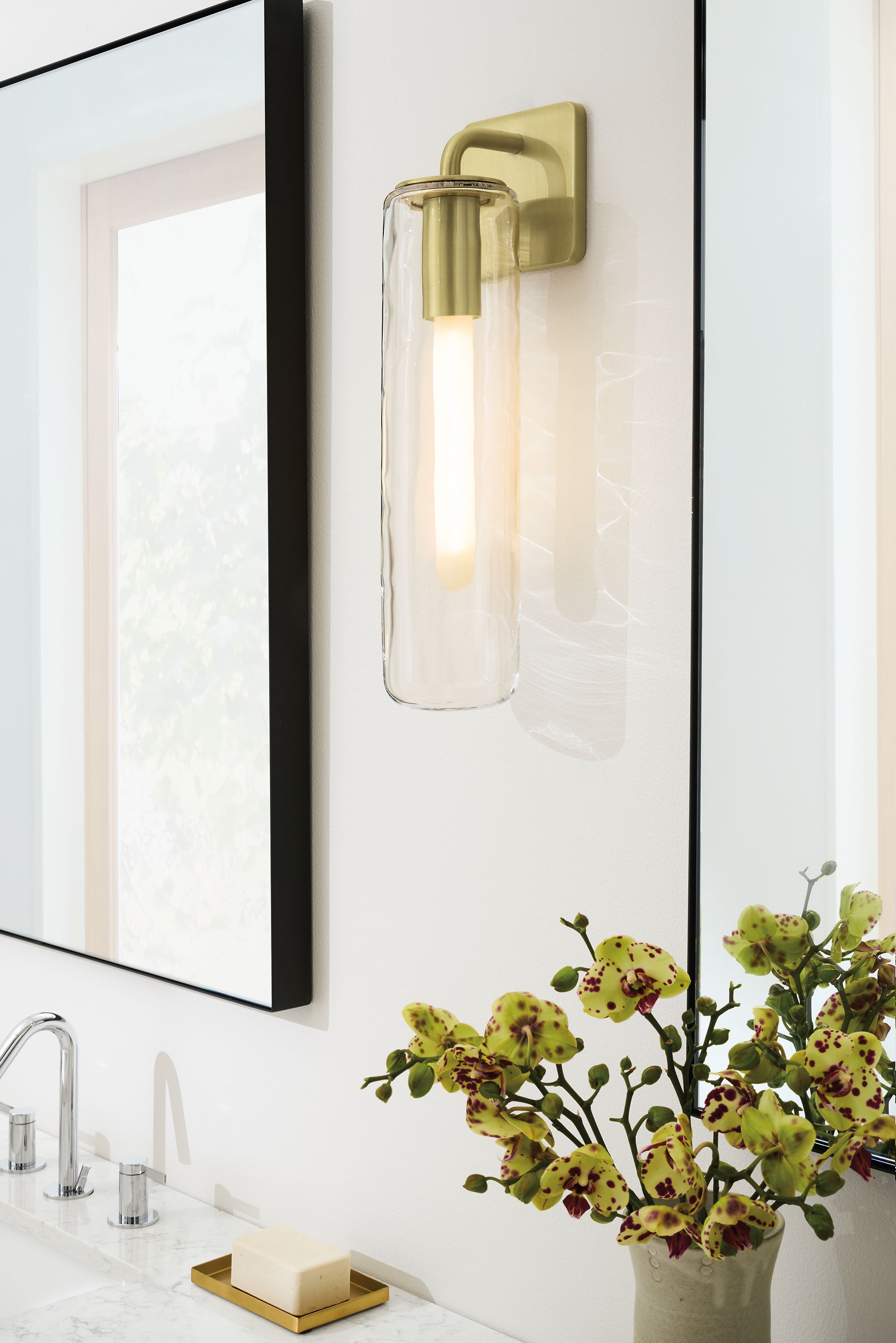 Bathroom with detail of Ursa 18.5-high wall sconce in clear glass and brushed gold powdercoat and 2 infinity wall mirrors in graphite.