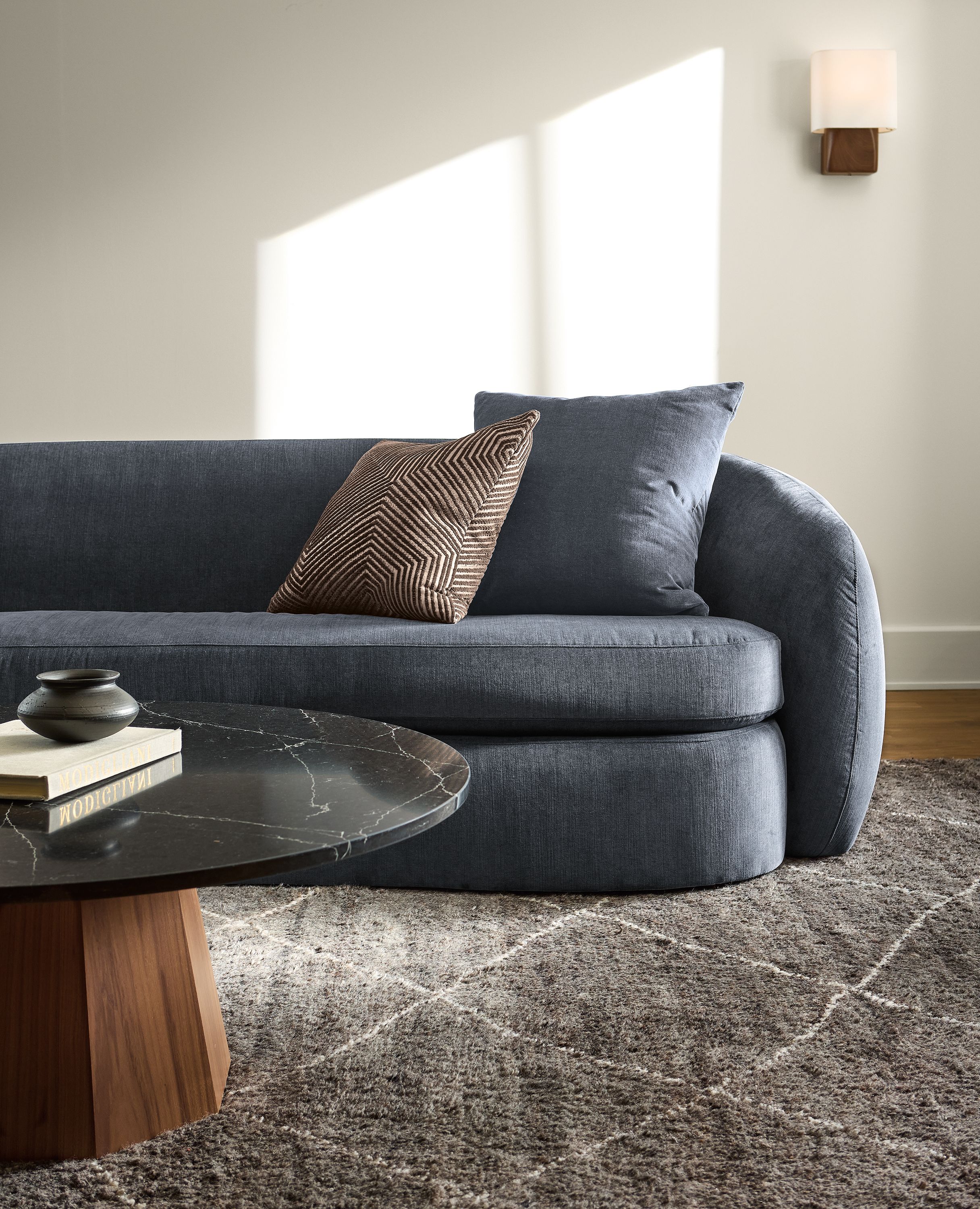 Living room with Valora benchseat sofa in windsor navy, Glover round coffee table in walnut and black marbled quartz and kalindi rug in charcoal.