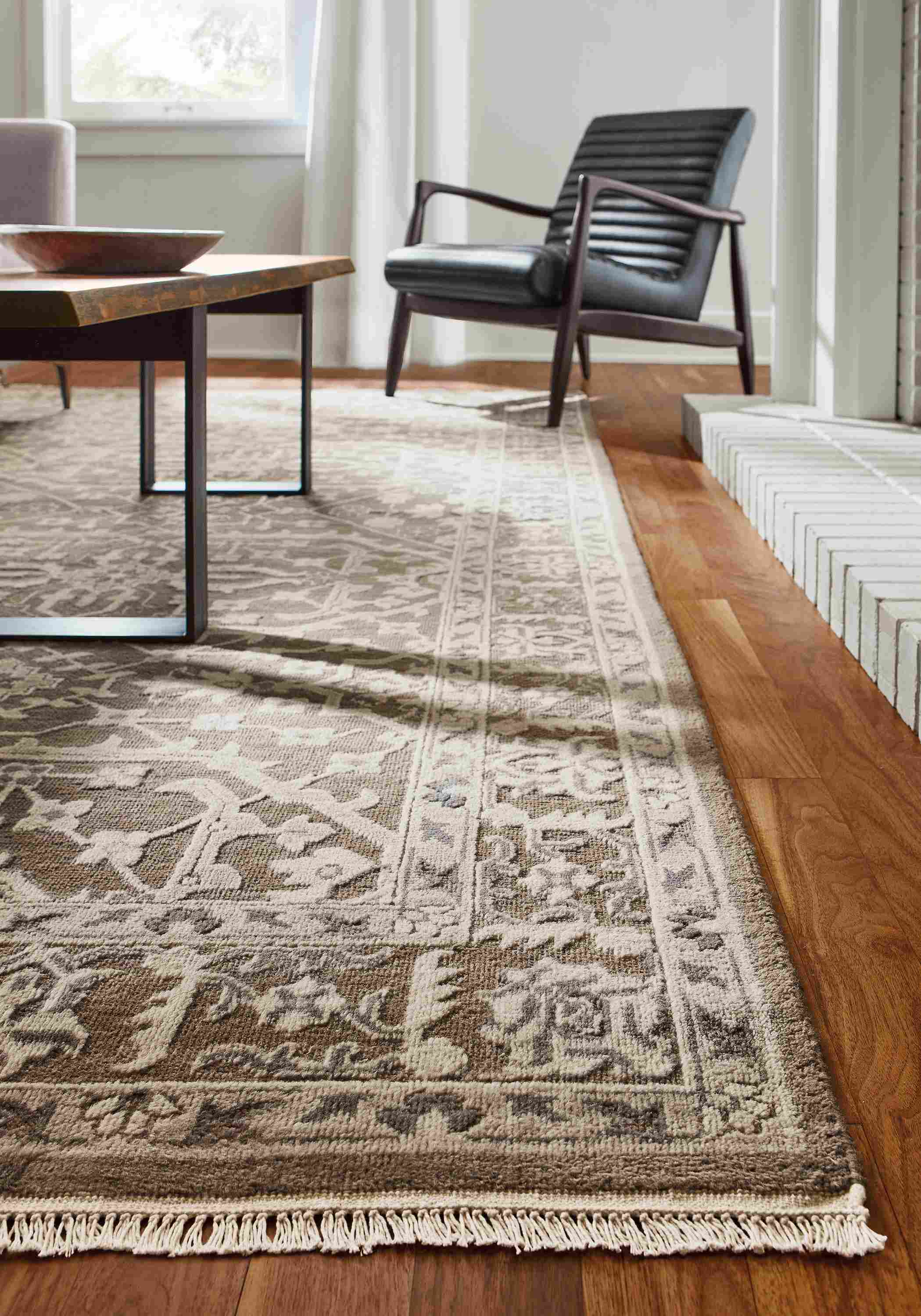 Detail of Vanya rug in taupe and callan chair in Urbino Black leather.