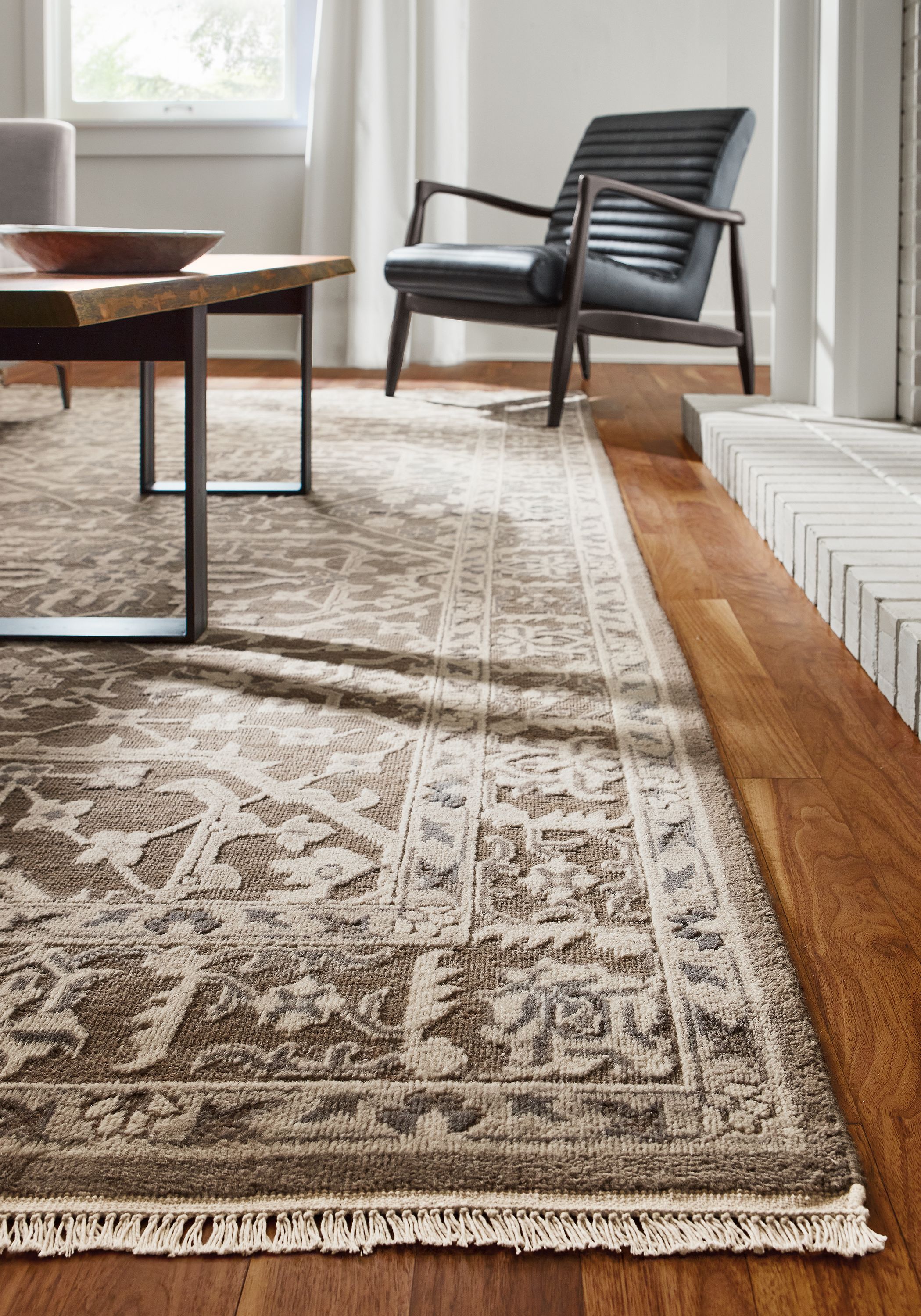 Detail of Vanya rug in taupe and callan chair in Urbino Black leather.