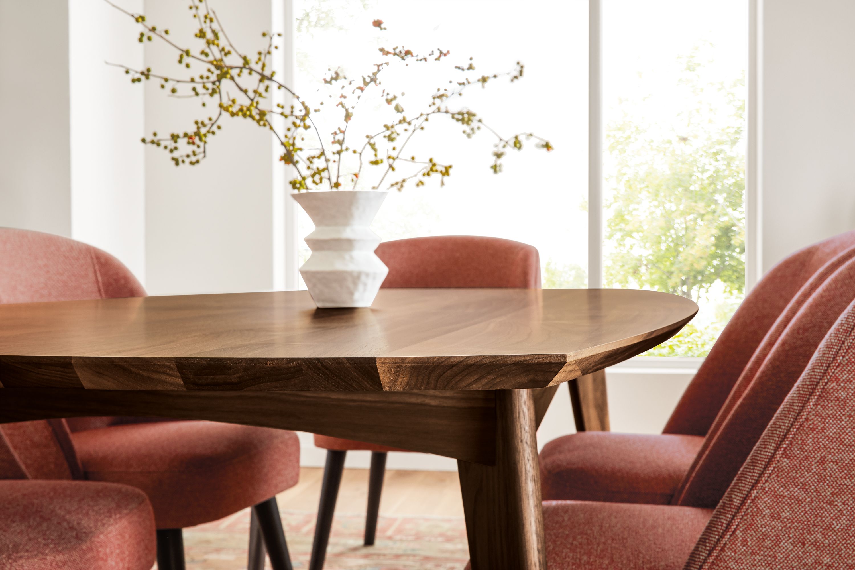 Detail of Ventura dining table in walnut and Cora side chairs in Tatum Spice fabric.
