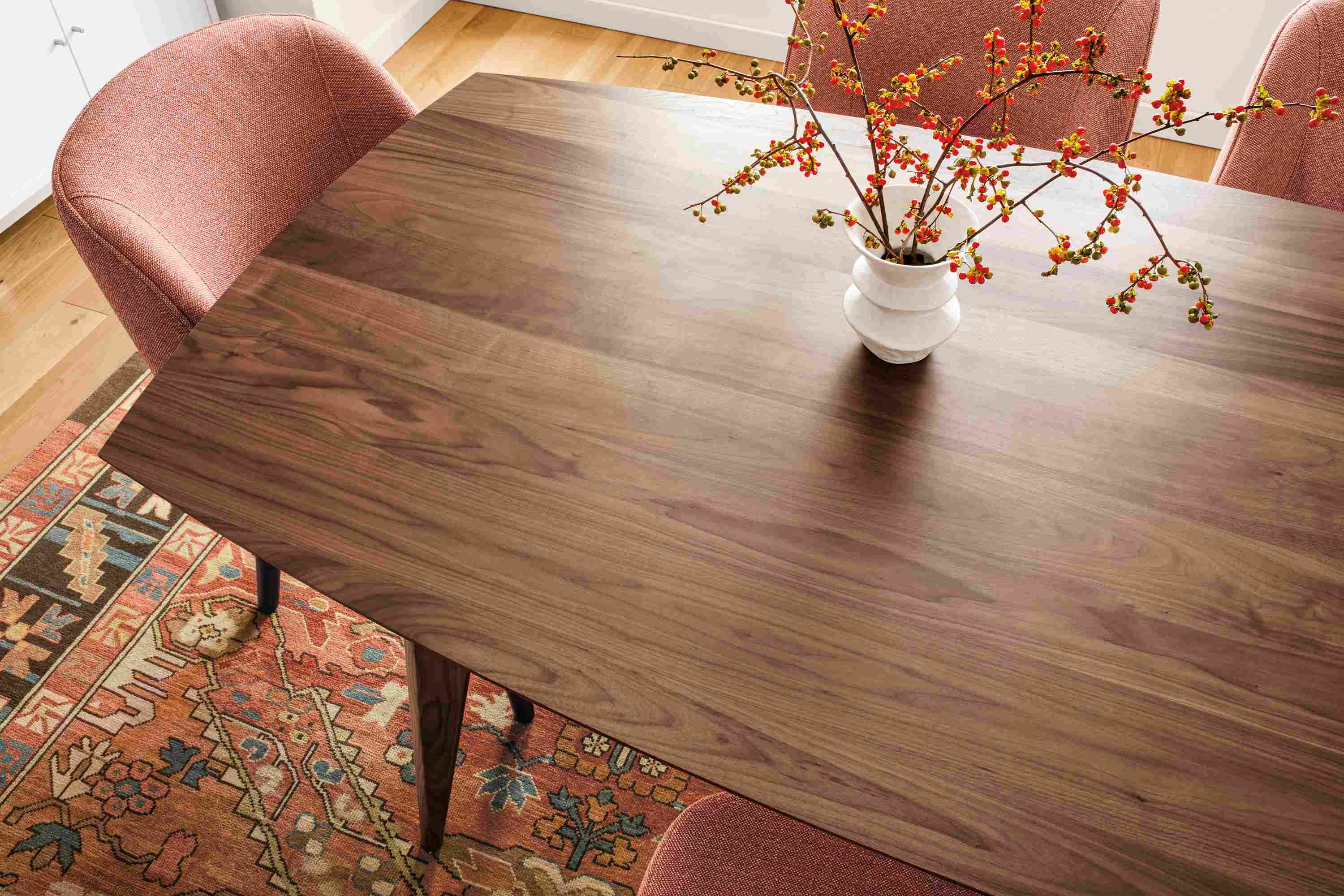 Overhead detail of large Ventura dining table in walnut and Cora side chairs in Tatum Spice.