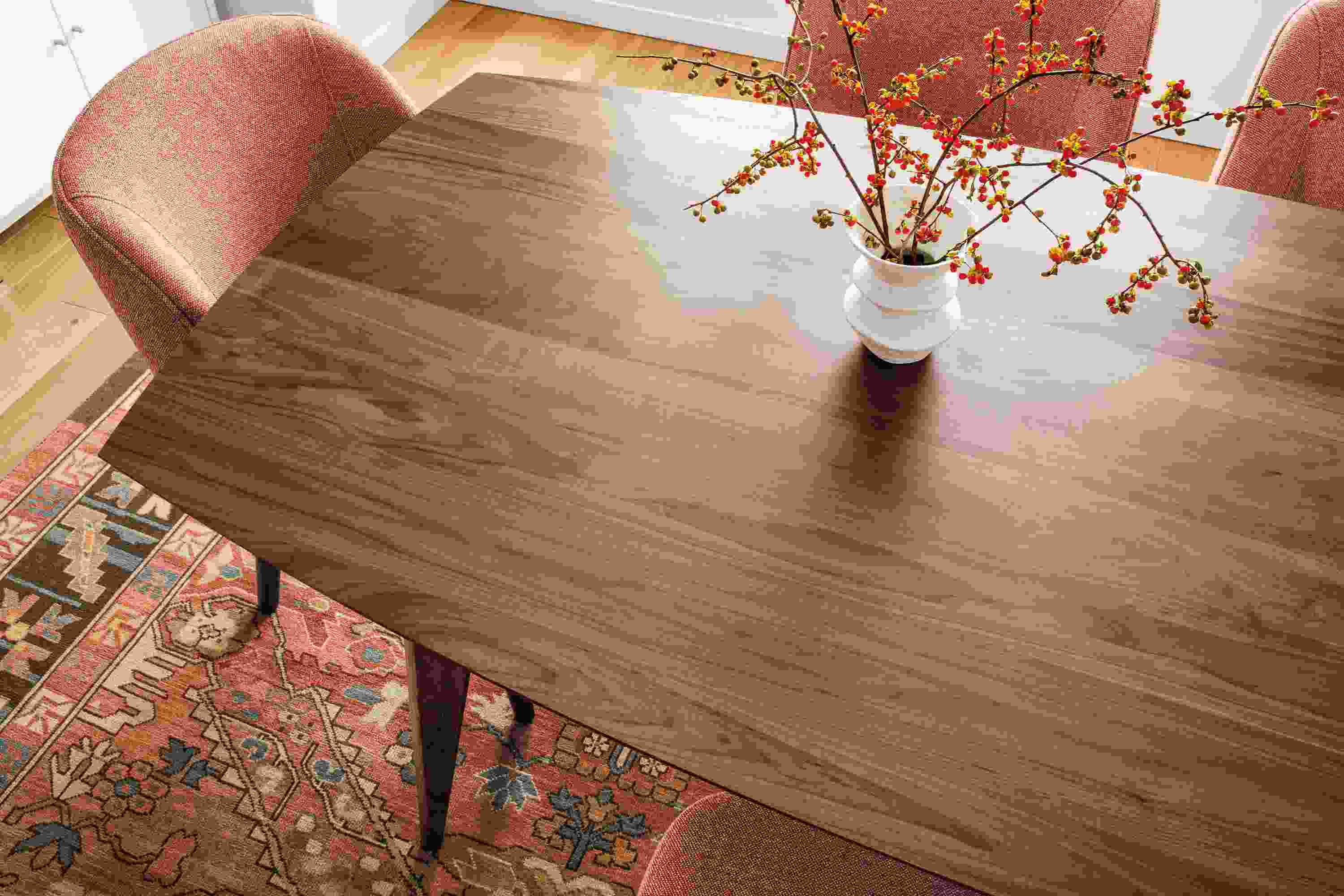 Overhead detail of large Ventura dining table in walnut and Cora side chairs in Tatum Spice.