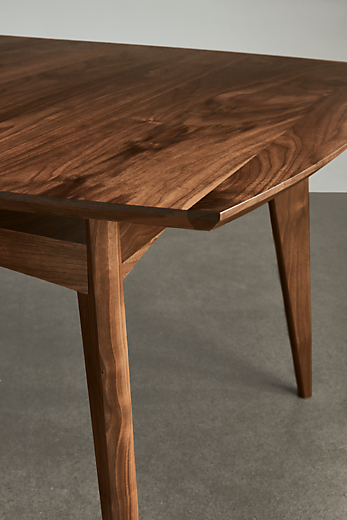 detail of ventura extension dining table in walnut standing on concrete floor.