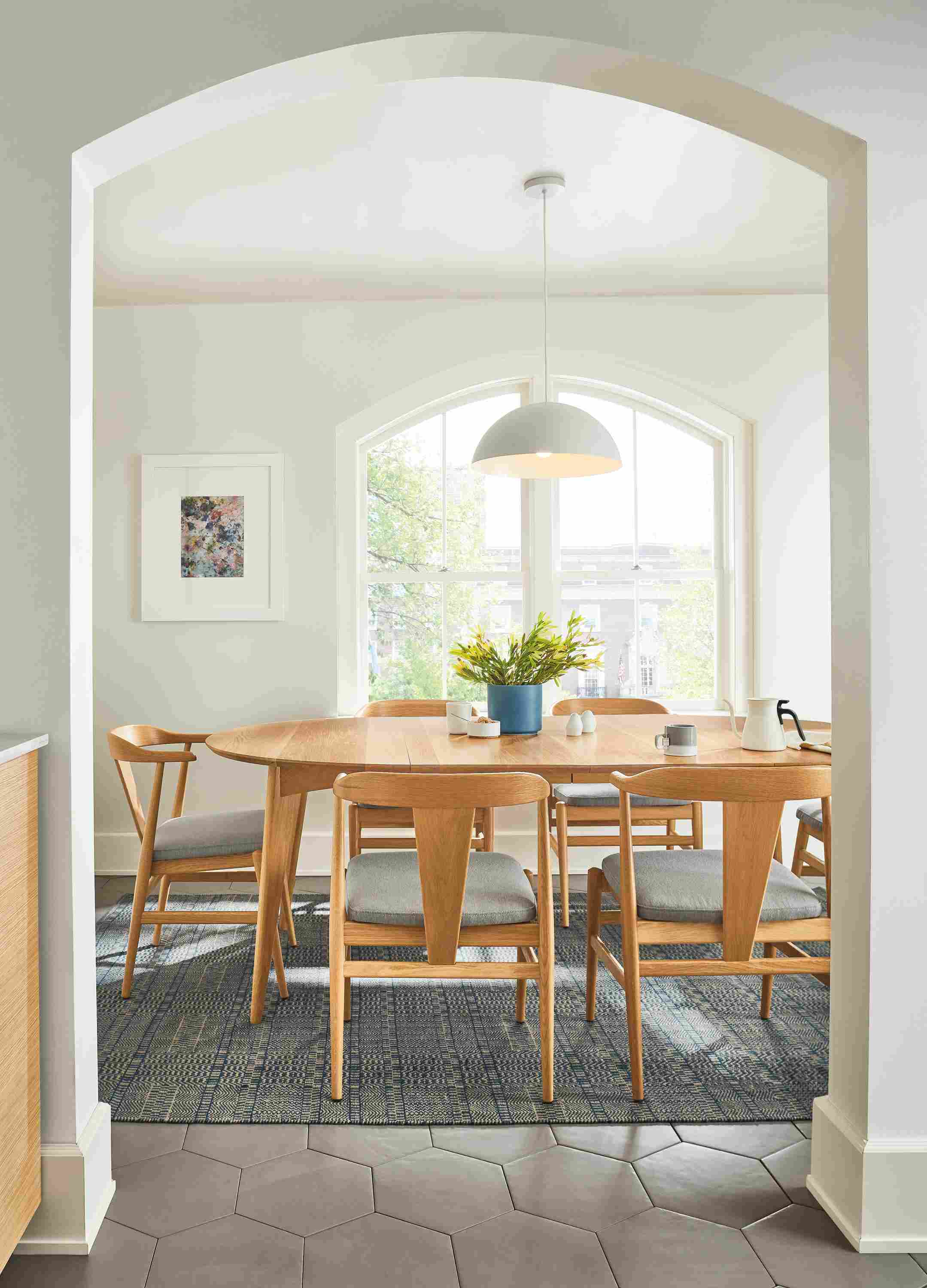 Look through a doorway into a dining room with Ventura extension table and 6 evan arm chairs all in white oak.