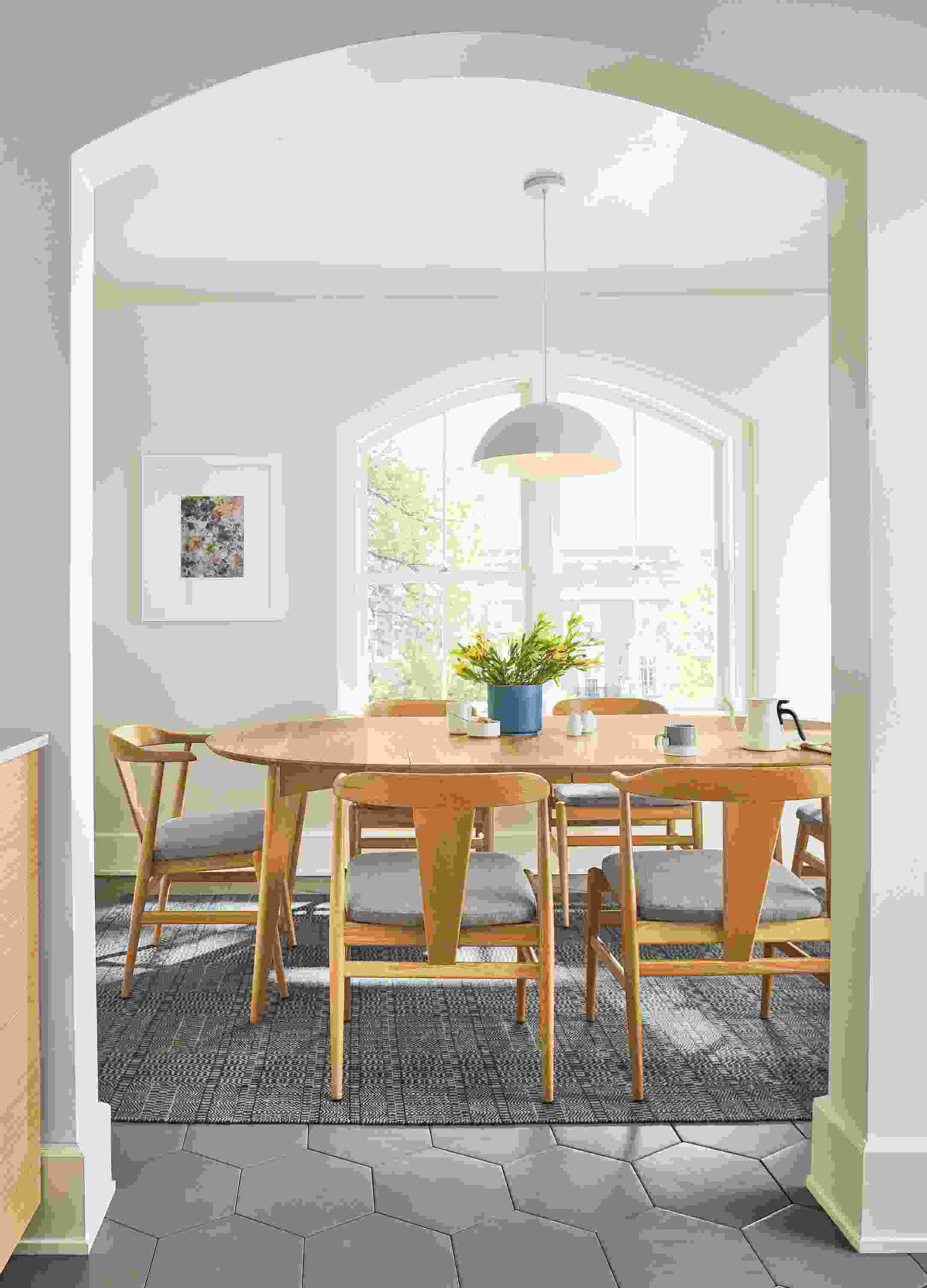 Look through a doorway into a dining room with Ventura extension table and 6 evan arm chairs all in white oak.