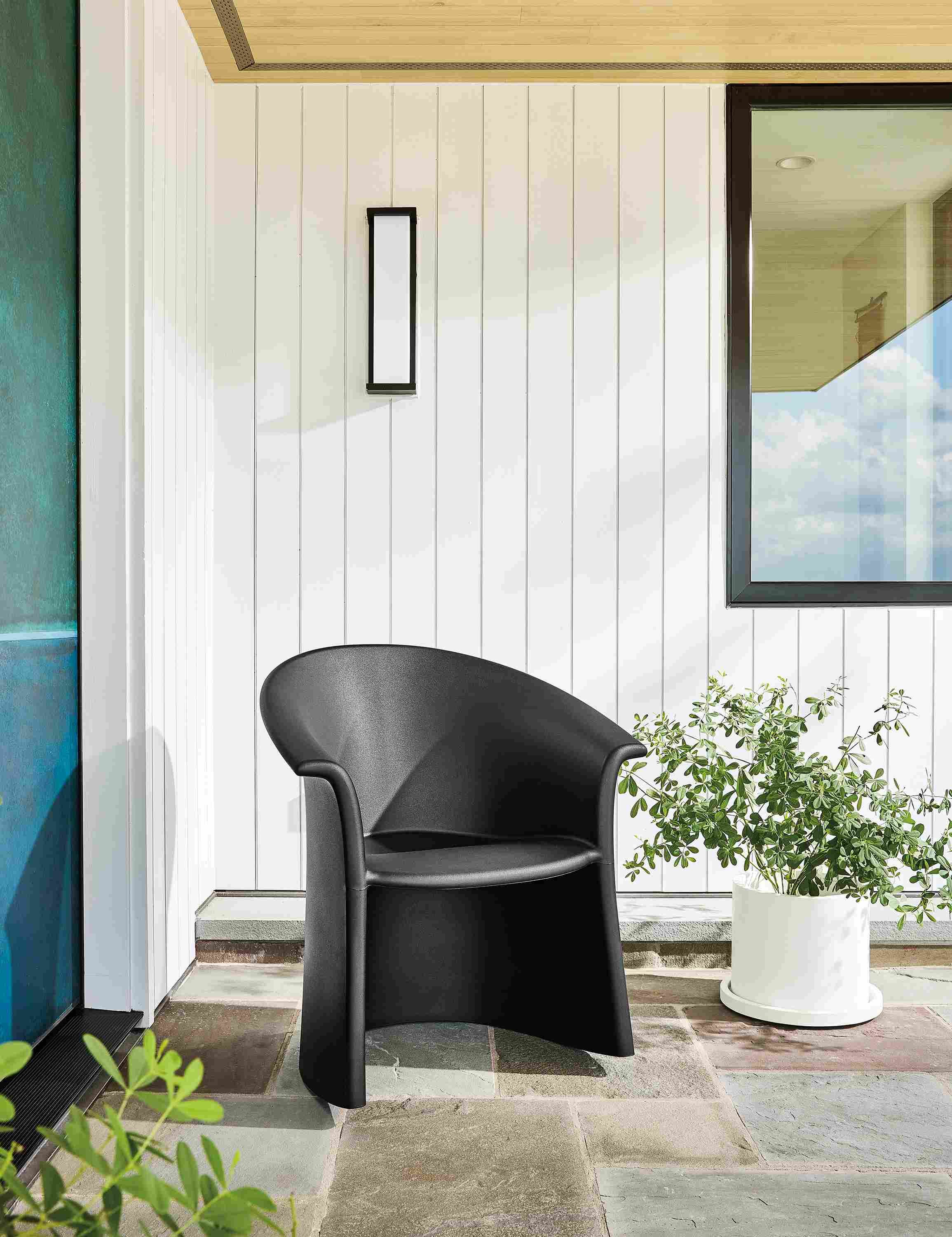 Outdoor seating area with vignelli rocker in black and renga 13-round planter with tray in white.